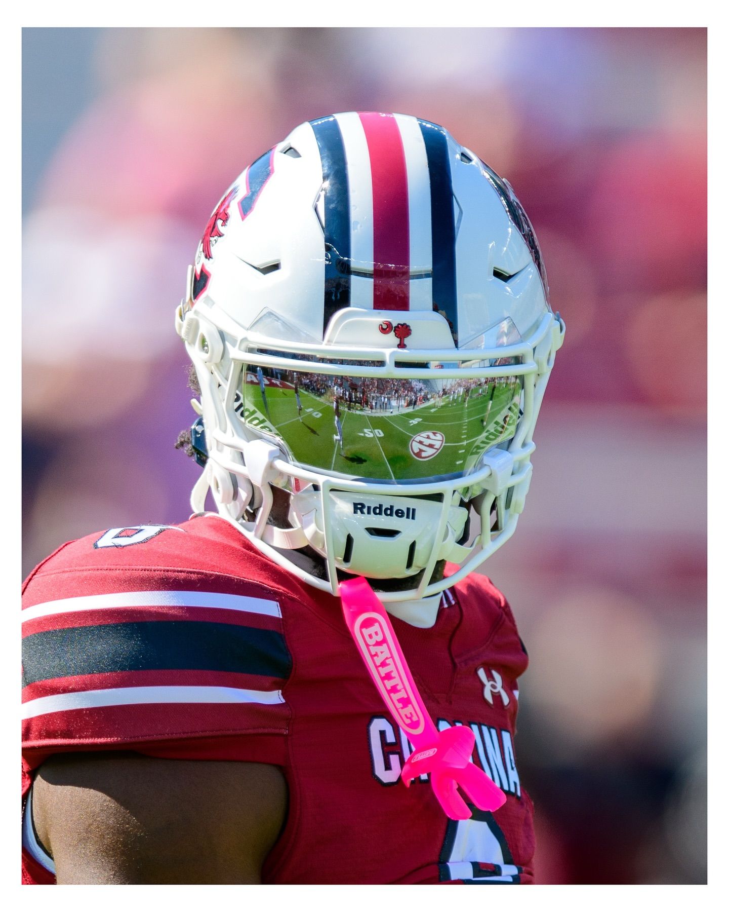 Close-up of a South Carolina football player’s white helmet, featuring a clear visor reflecting the stadium and field.