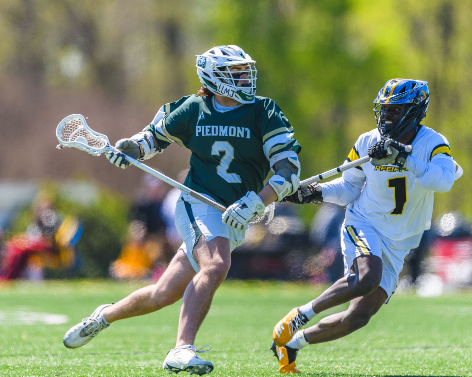 Piedmont University Lions lacrosse player Andrew Coffee #2 maneuvers past a defender during a collegiate game on a sunny day.