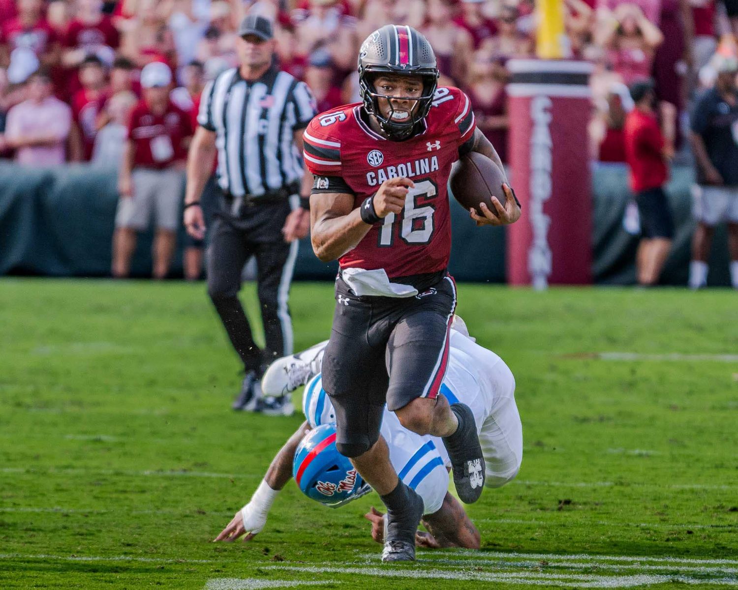 A South Carolina football player in a garnet jersey sprints downfield while breaking away from a tackle.