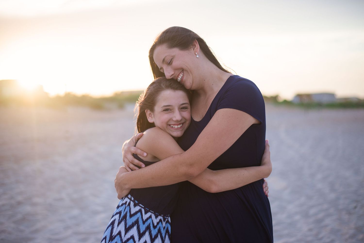 Mother hugging child in golden backlit sunset — emotional natural light portrait by Alexandra Hall, Jacksonville FL