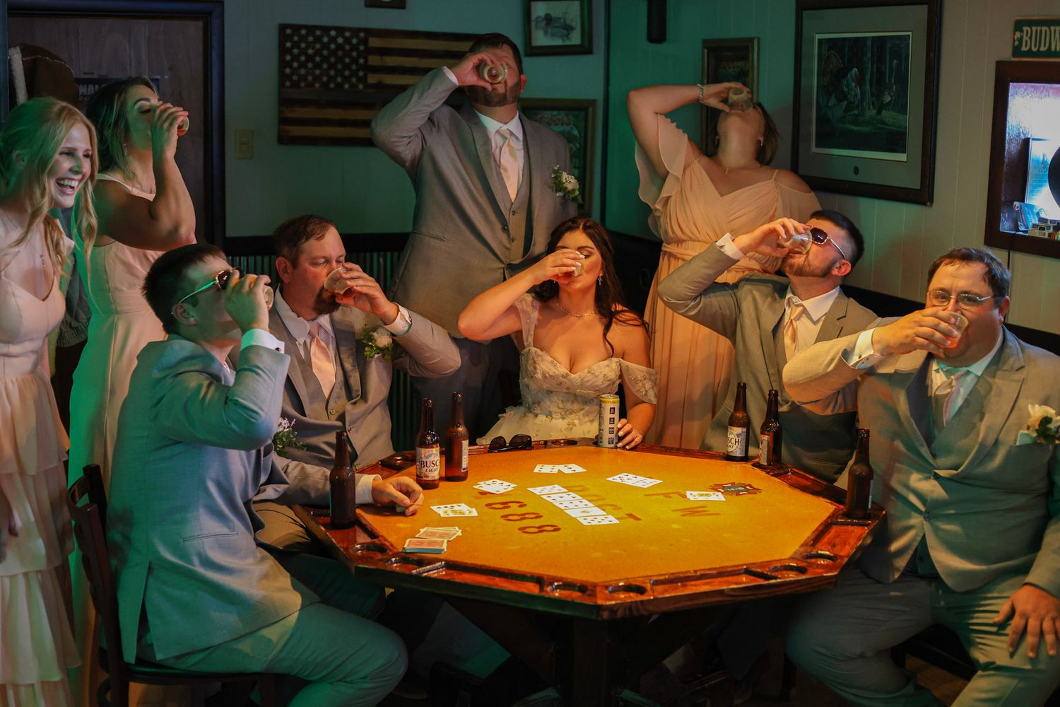 Wedding party doing shots together around a poker table in a rustic bar.