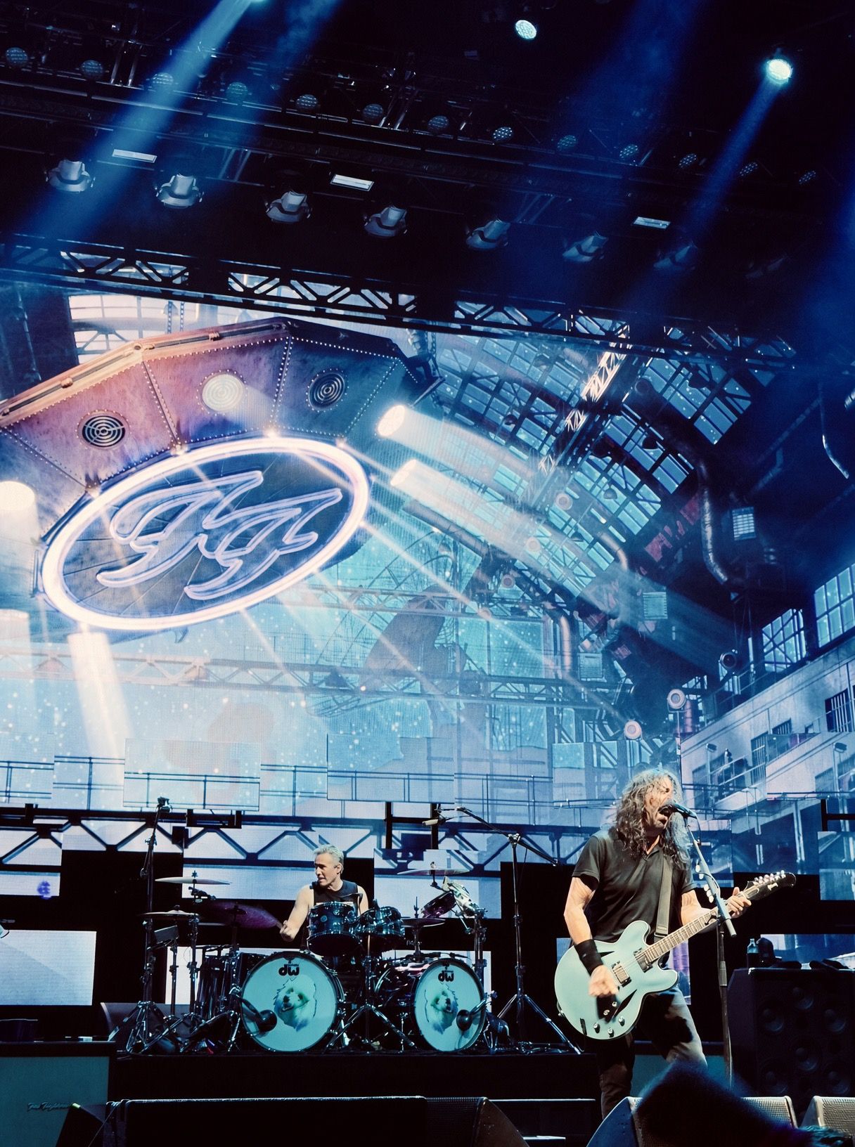 Foo Fighters performing live on stage with dramatic blue lighting and iconic FF logo backdrop.