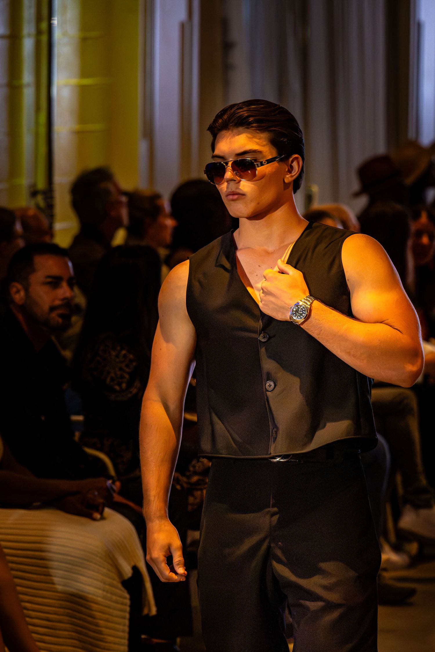 Model wearing a black sleeveless vest and sunglasses on the Charlotte Fashion Week runway.