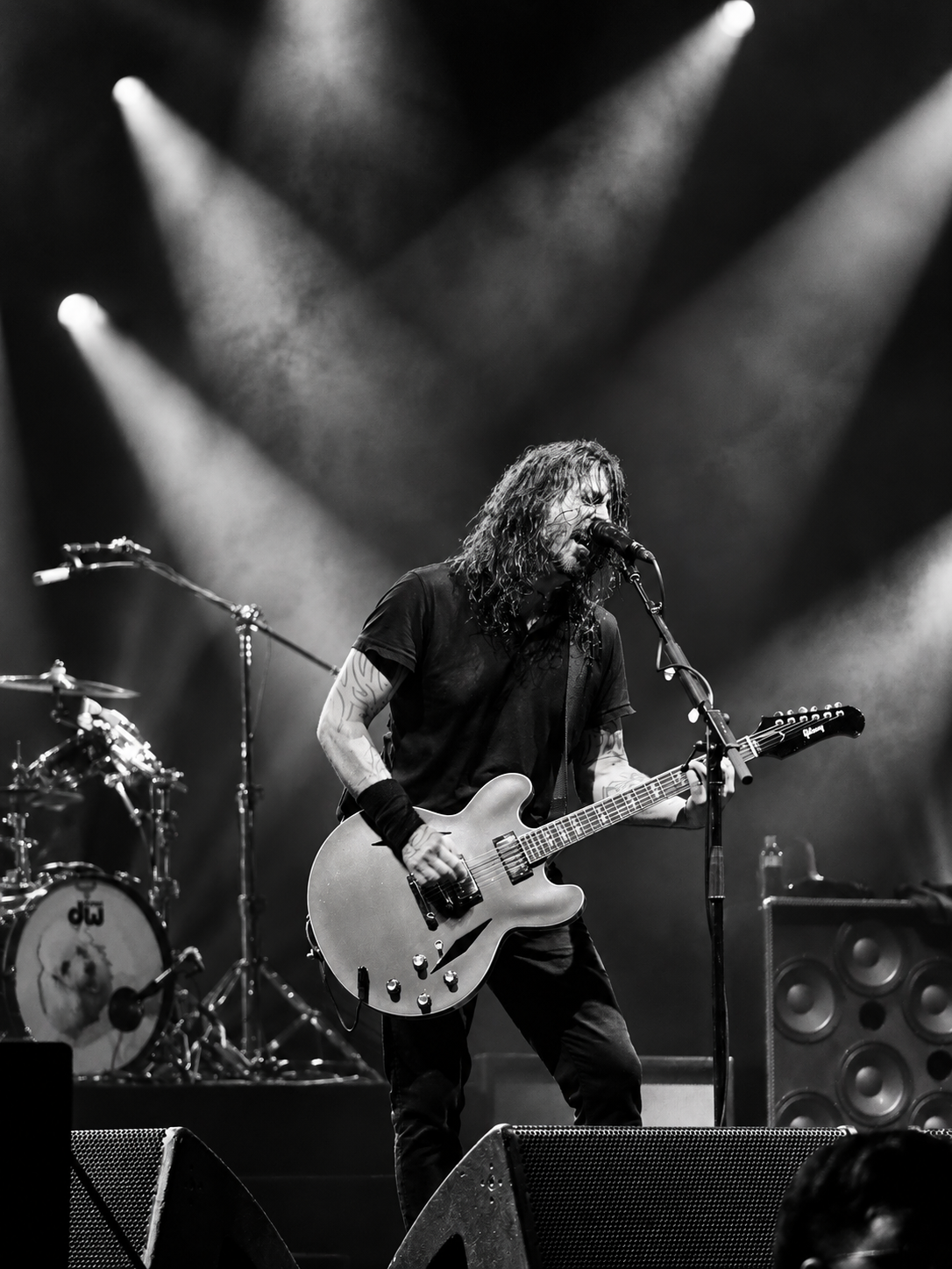 Black and white photo of a rock guitarist performing on stage with dramatic lighting and a microphone stand.