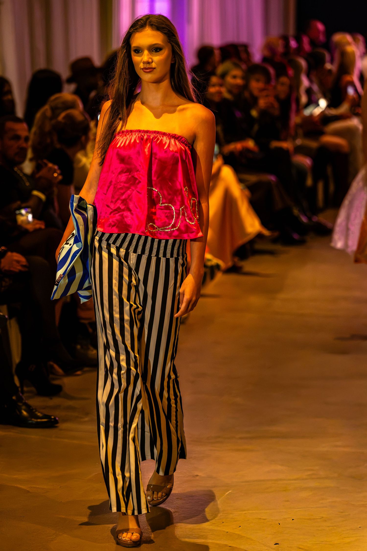 Model wearing a pink ruffled strapless top and black-and-white striped trousers at Charlotte Fashion Week.