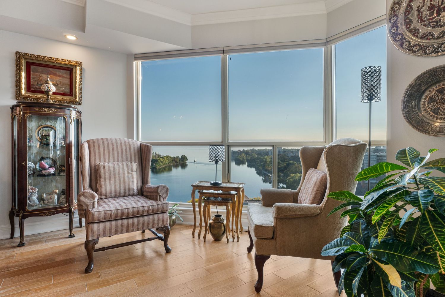 Elegant living room with two wingback chairs, a small table, and floor-to-ceiling windows overlooking a serene waterfront view.