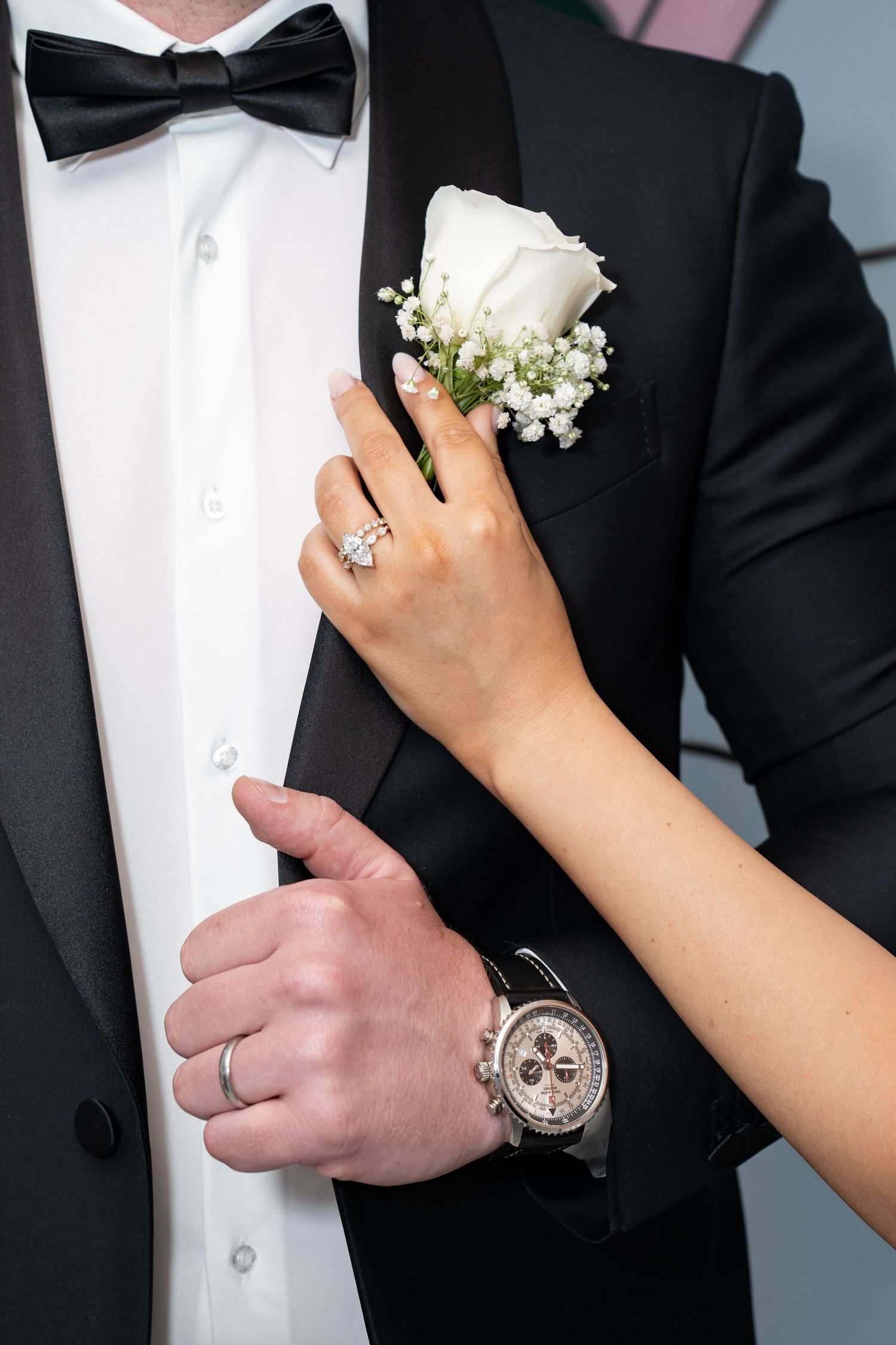 Bride's hand with diamond ring and groom's hand with watch on black tuxedo lapel. Las Vegas elopement photographer