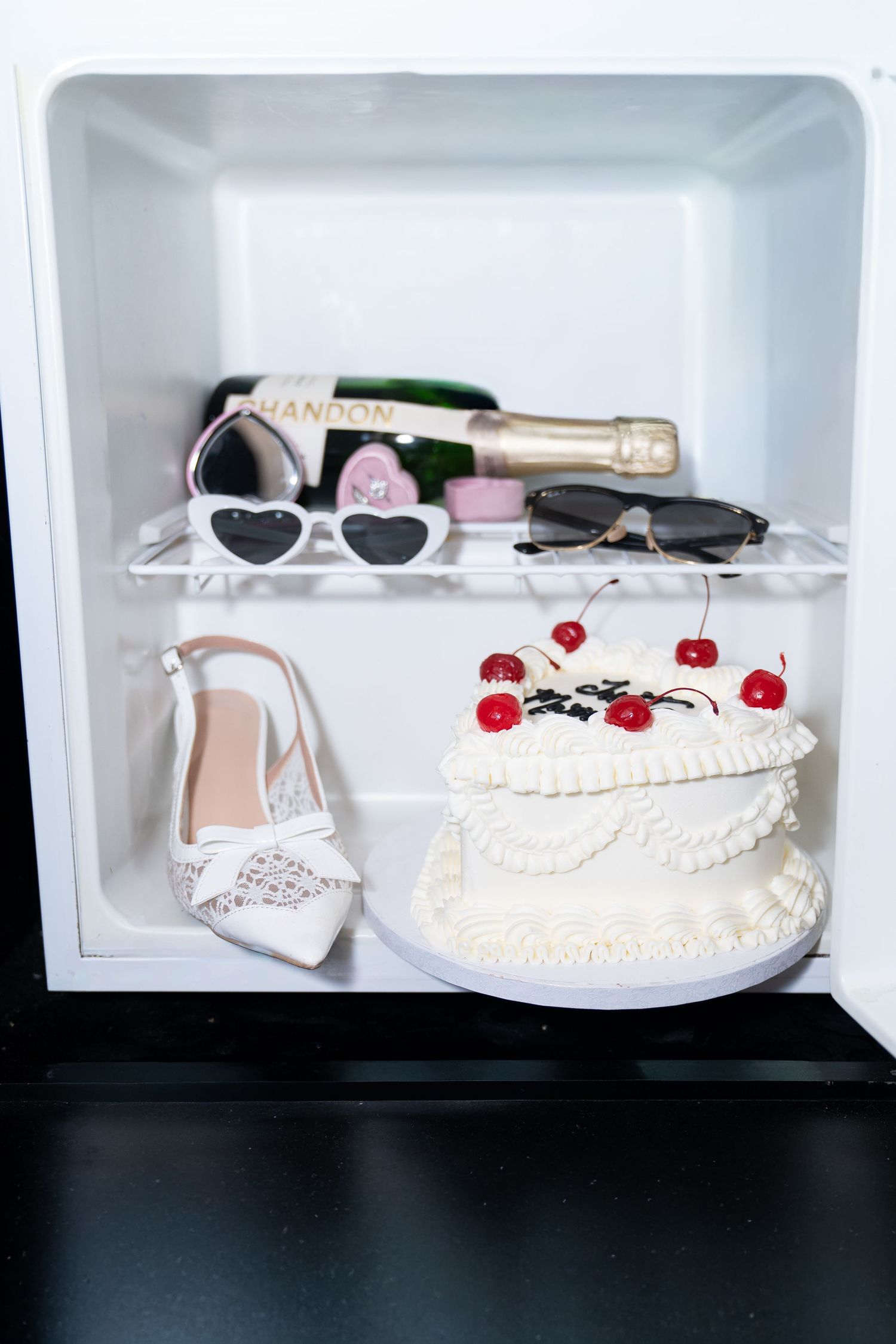 Mini fridge with wedding cake, champagne, sunglasses, and bridal heel shoes inside. Las Vegas elopement photographer