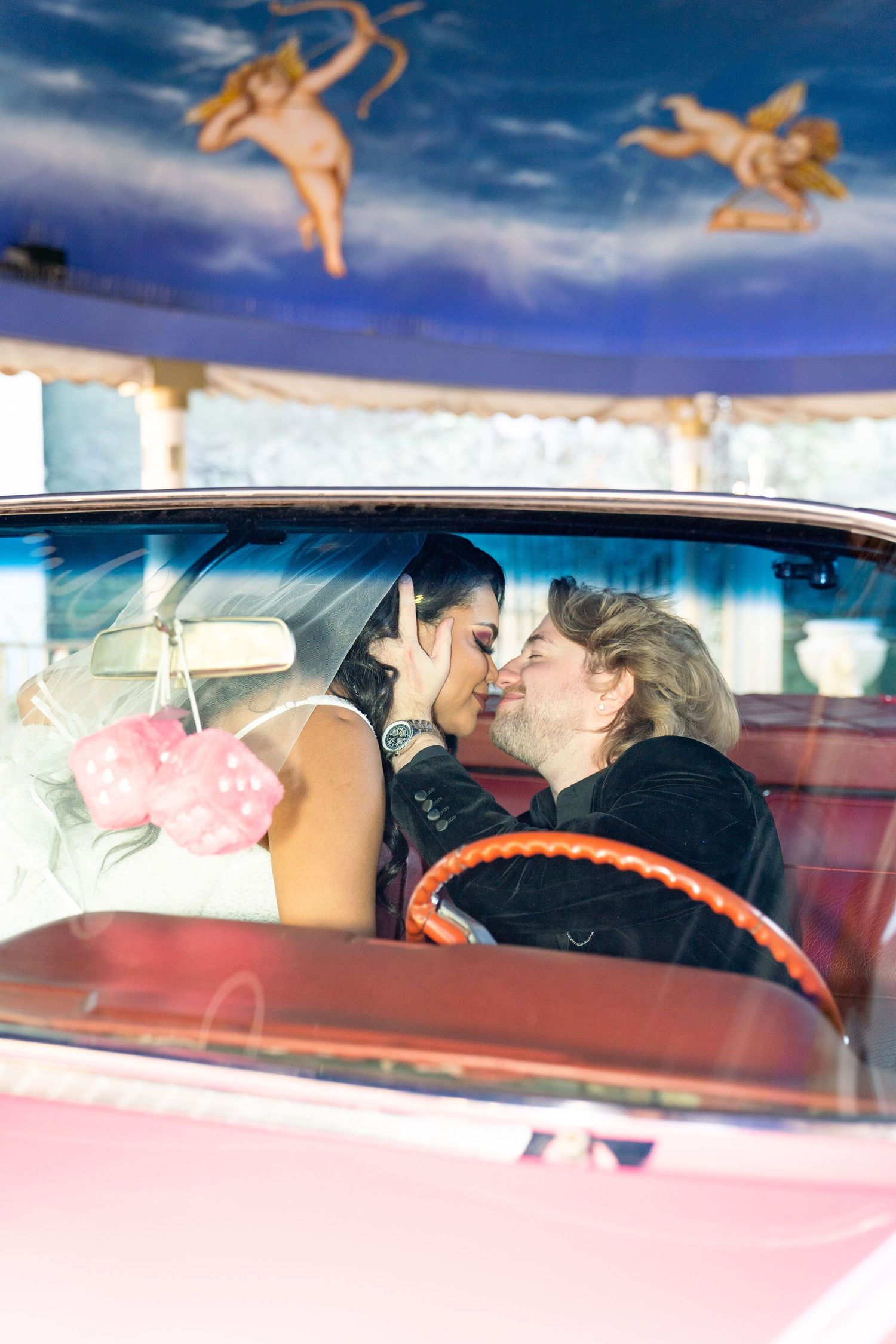 Newlyweds lean in for a kiss inside the iconic pink cadillac. Las Vegas elopement photographer