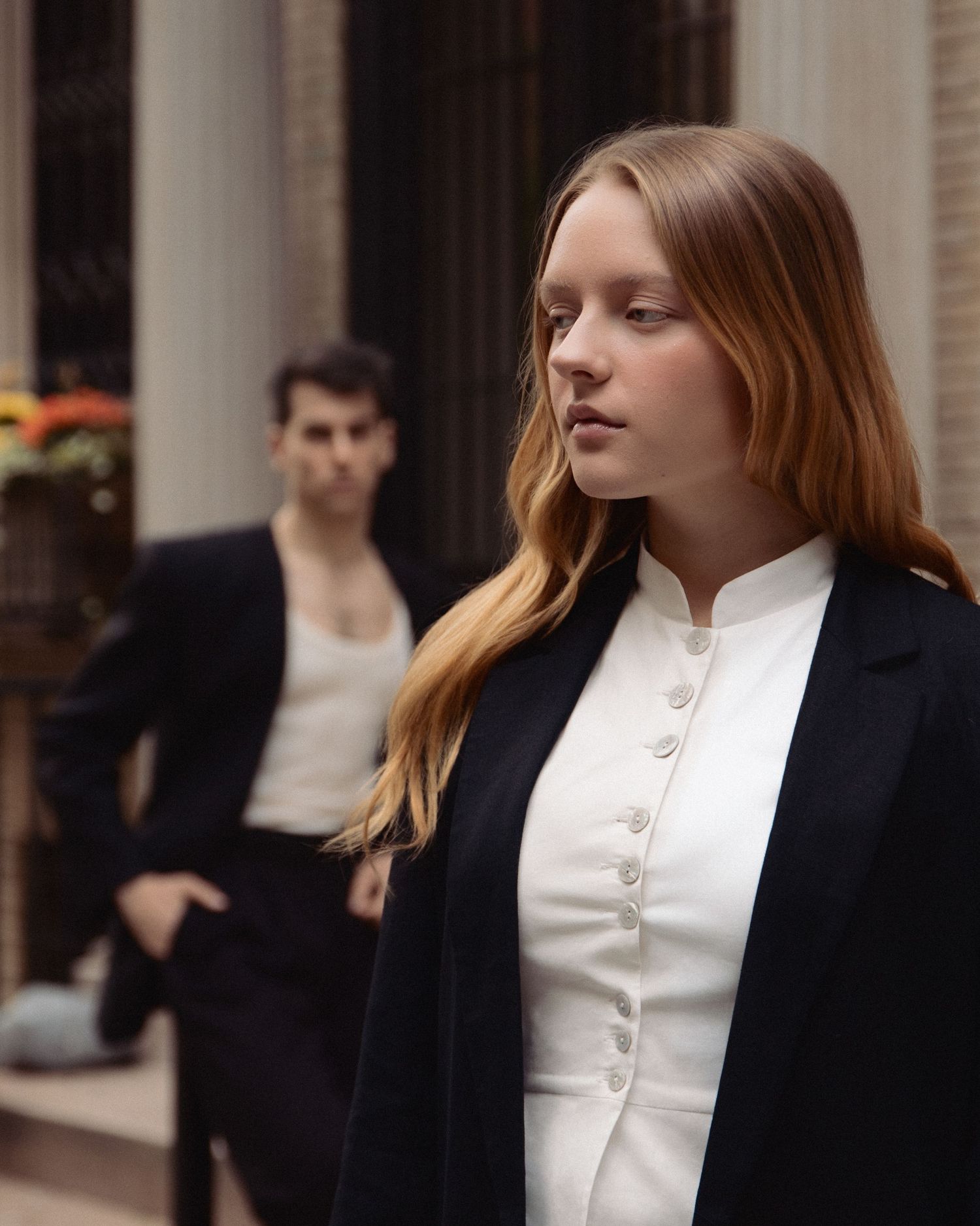 Regina fills the foreground in a close editorial portrait while Vin stands softly out of focus behind her on an Upper West Side stoop.