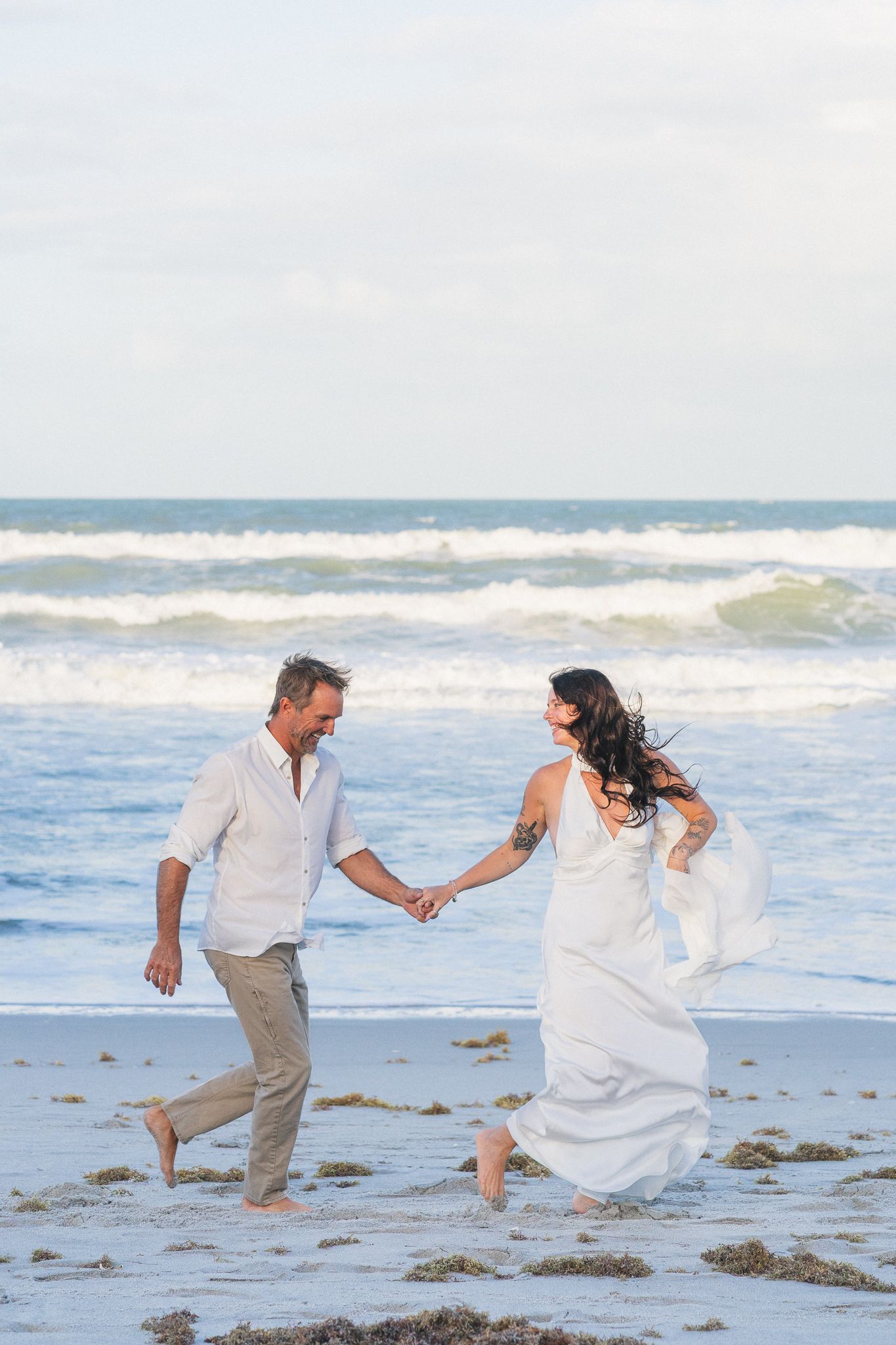 Couple walking on the beach during sunset engagement session in Melbourne, Florida