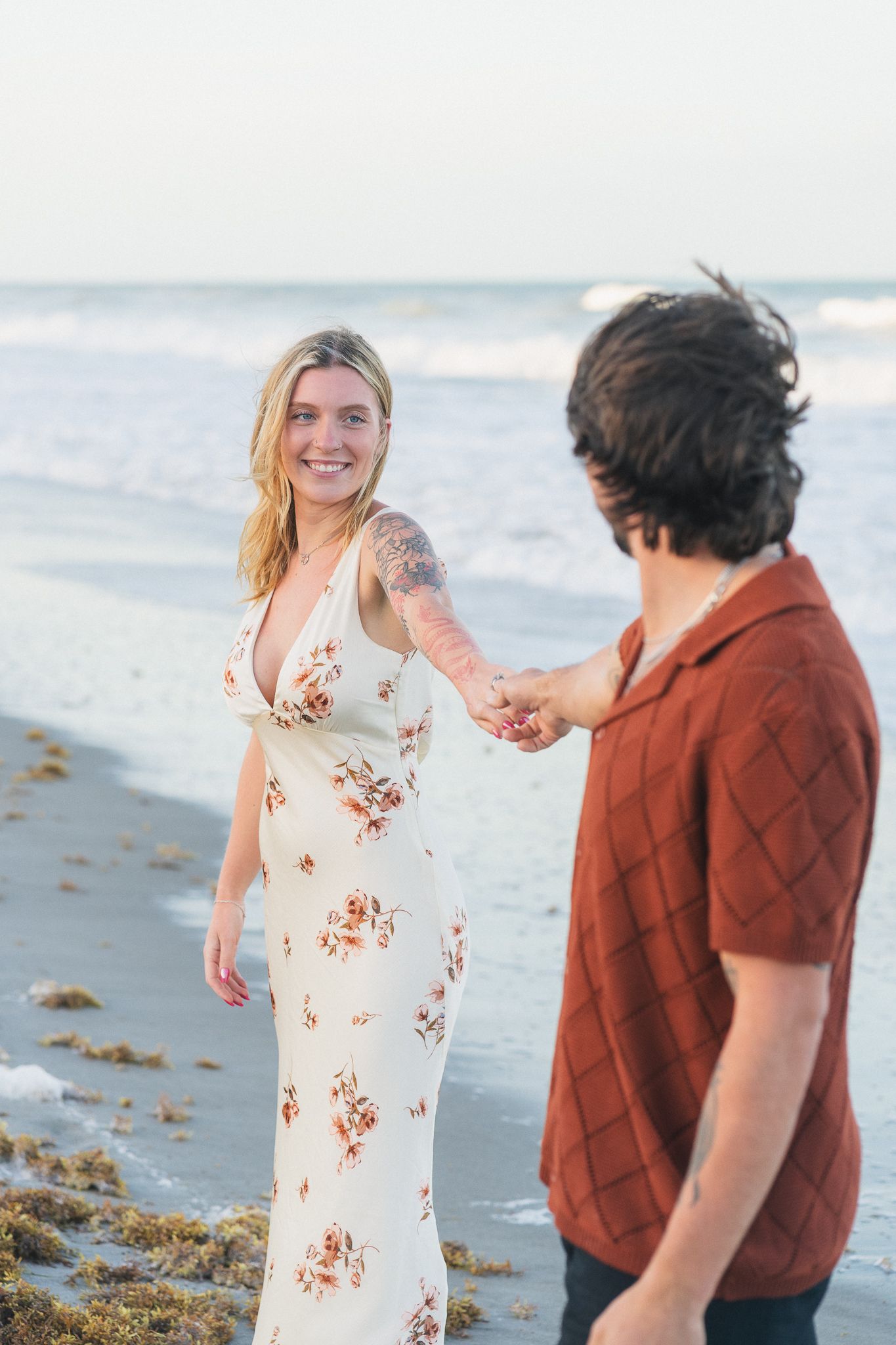 Couple walking on the beach during sunset engagement session in Melbourne, Florida