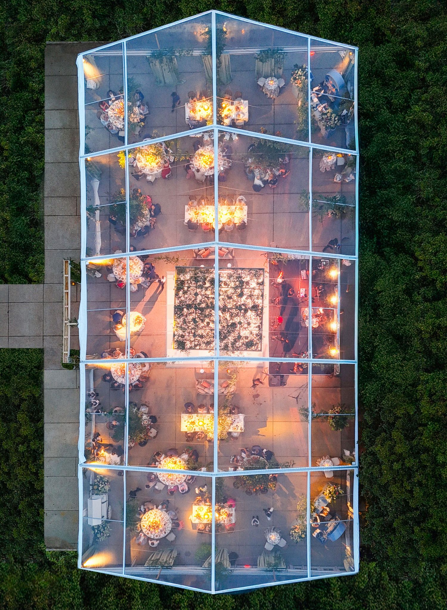 Aerial view of a modern glass building with illuminated orange lights creating a glowing pattern at dusk.