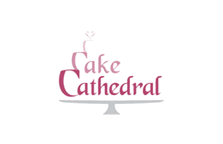 A white wedding cake with pink floral decorations sits on display at a cathedral venue.