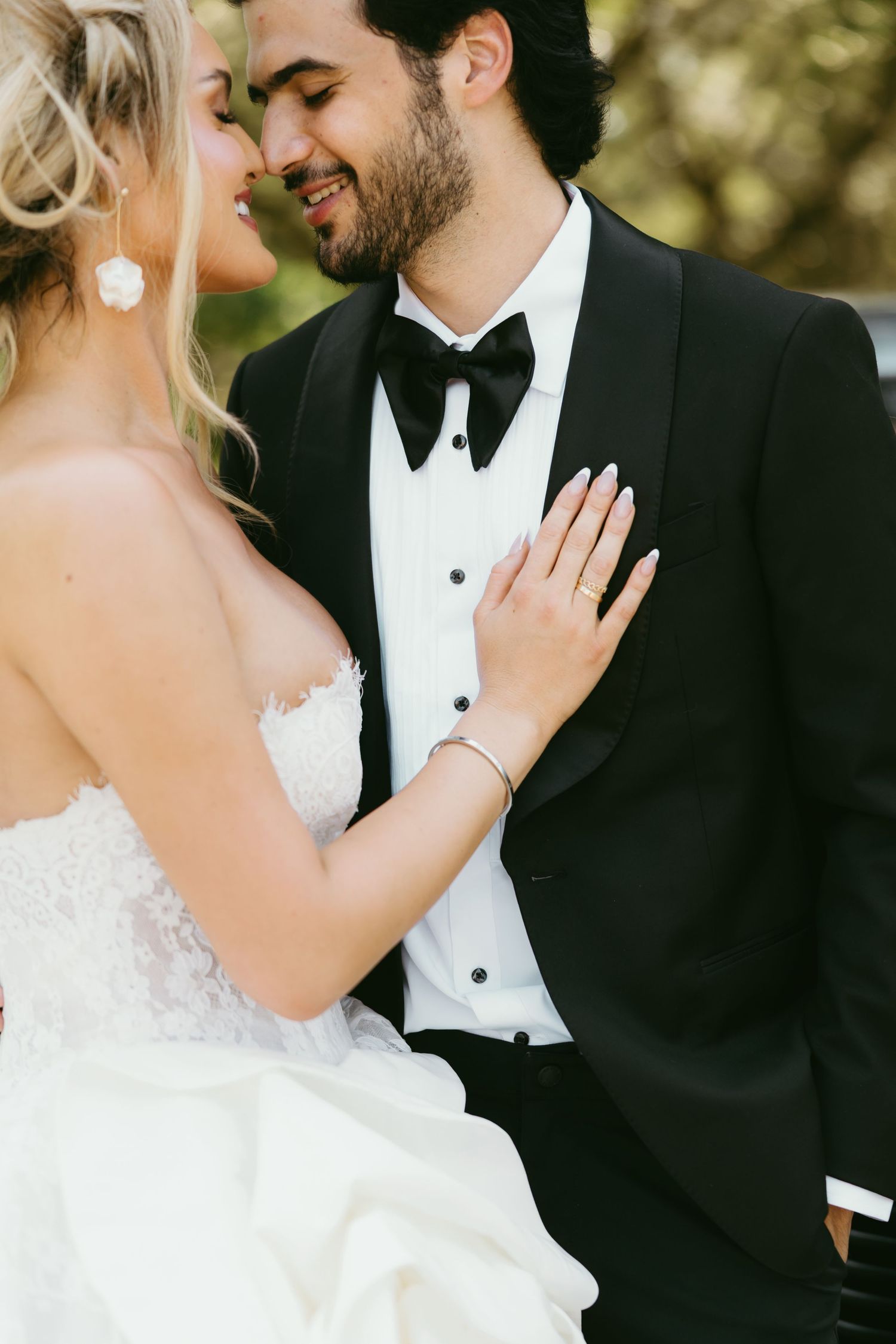 A romantic moment between newlyweds in formal wedding attire during an outdoor photo session.