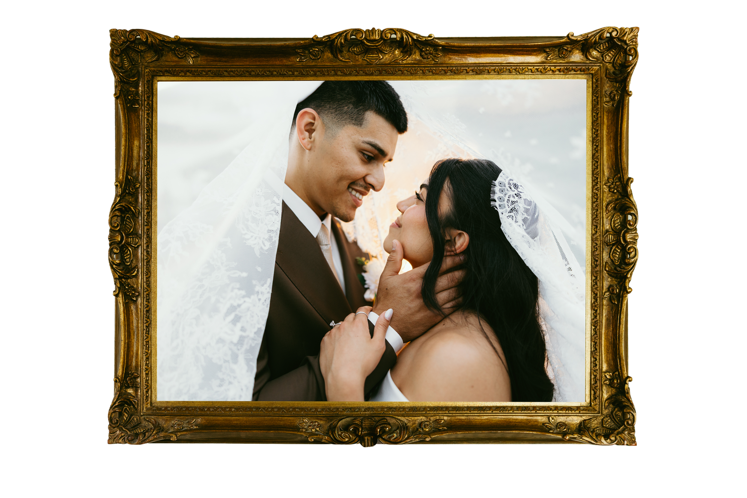 Couple sharing a romantic moment in wedding attire, framed in an ornate gold picture frame.