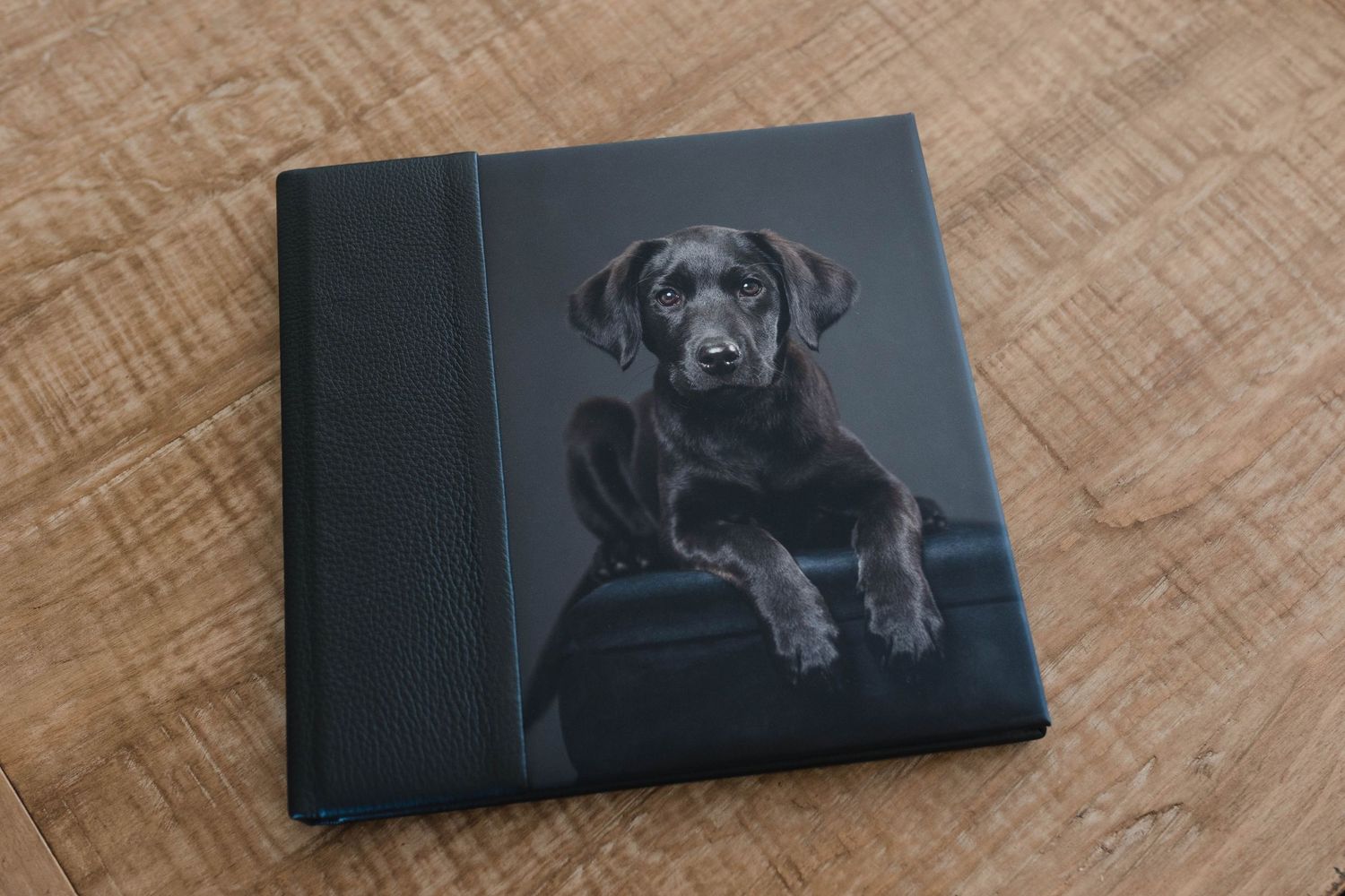 A black leather wallet with an engraved dog portrait sits on a wooden surface.
