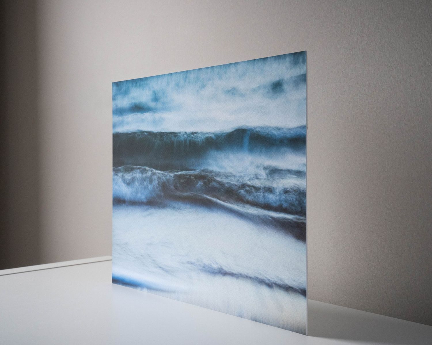 A series of minimalist landscape paintings displayed on a white wall in a gallery setting.