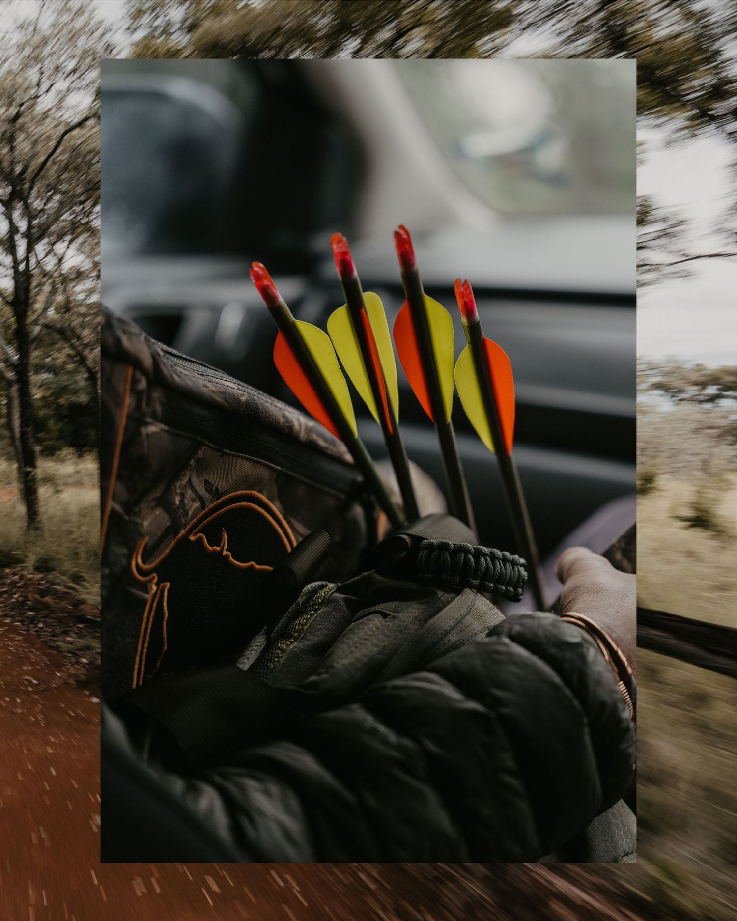 Archer holding colorful arrows with orange and yellow fletching while riding in a vehicle.