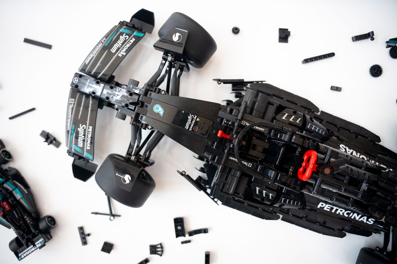 Top view of LEGO Mercedes-AMG Petronas F1 car model partially assembled on white surface.