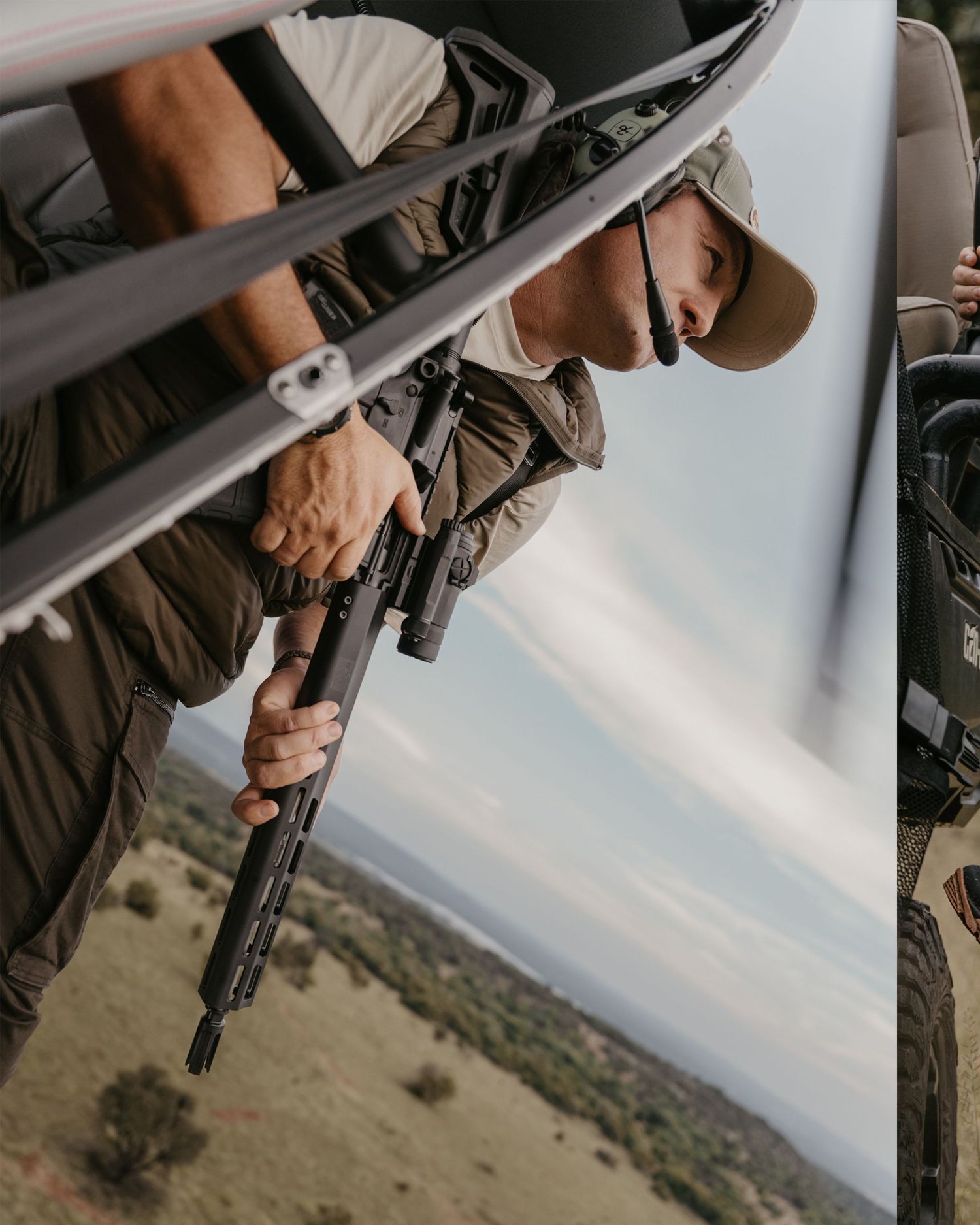 Hunter leaning out of vehicle holding rifle over African savanna landscape below.