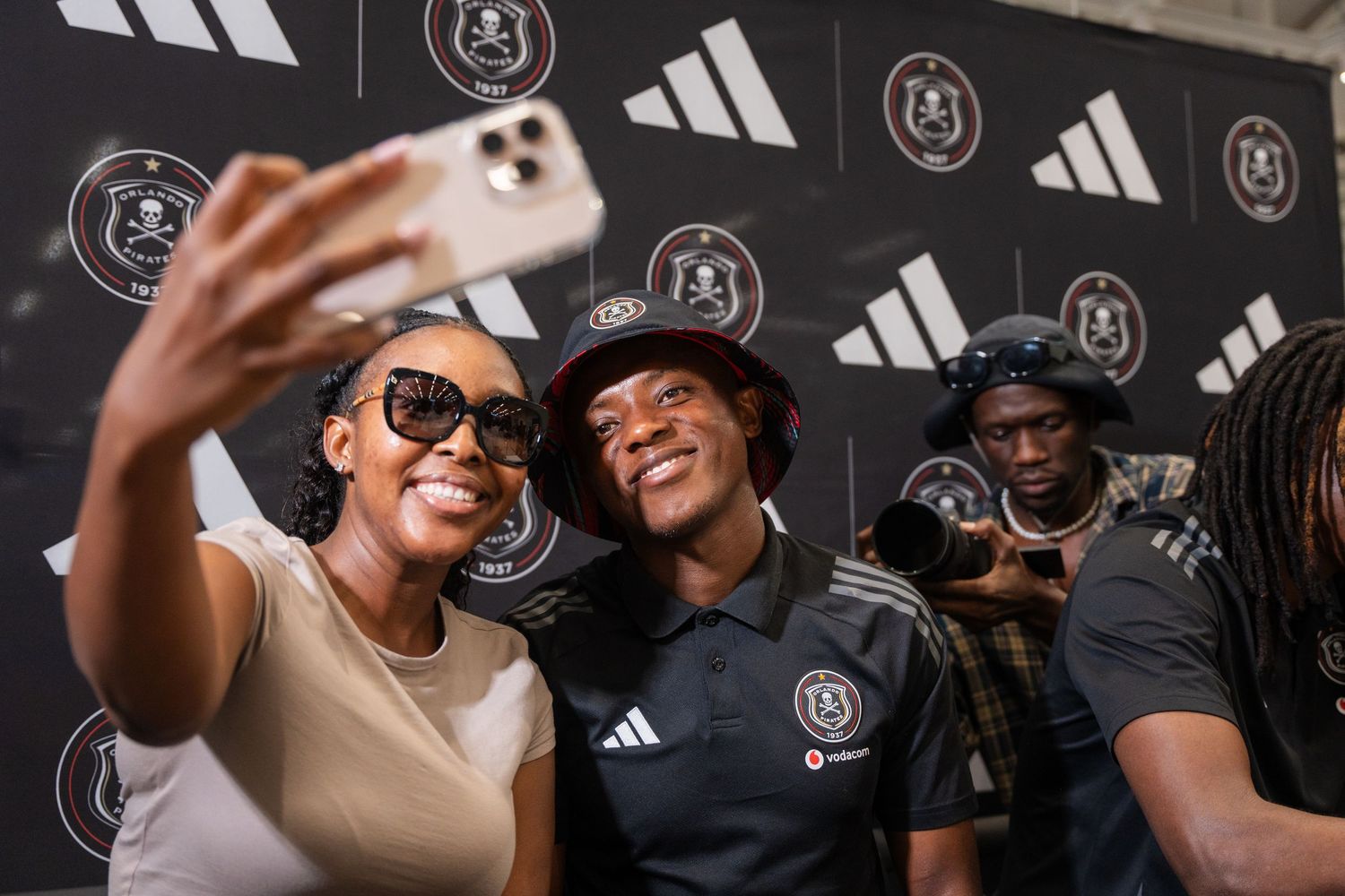 Orlando Pirates footballer poses for selfie with smiling female fans at Adidas event.