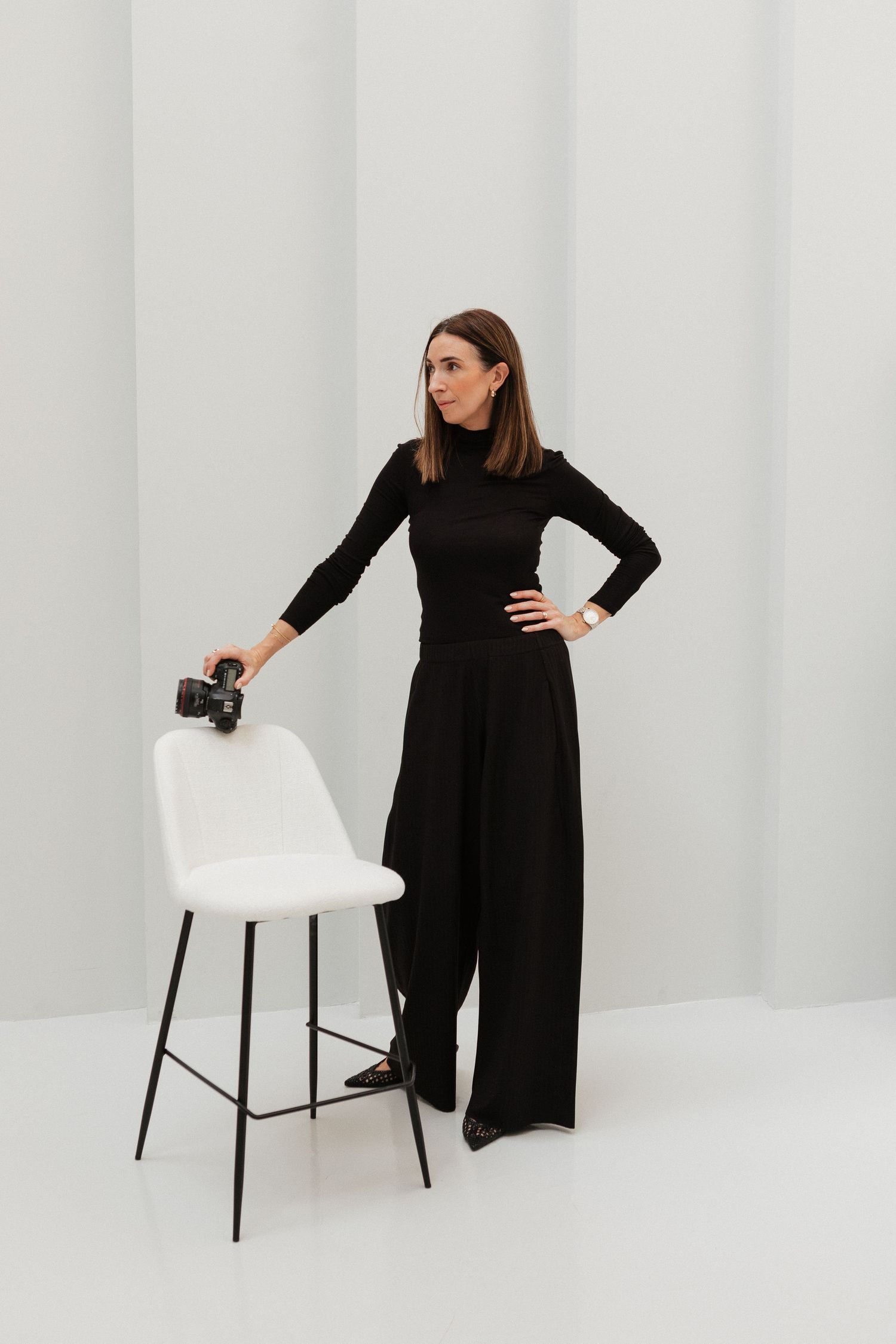 A person in a black outfit poses against a white backdrop in a series of professional studio photographs. Personal brand photographer.