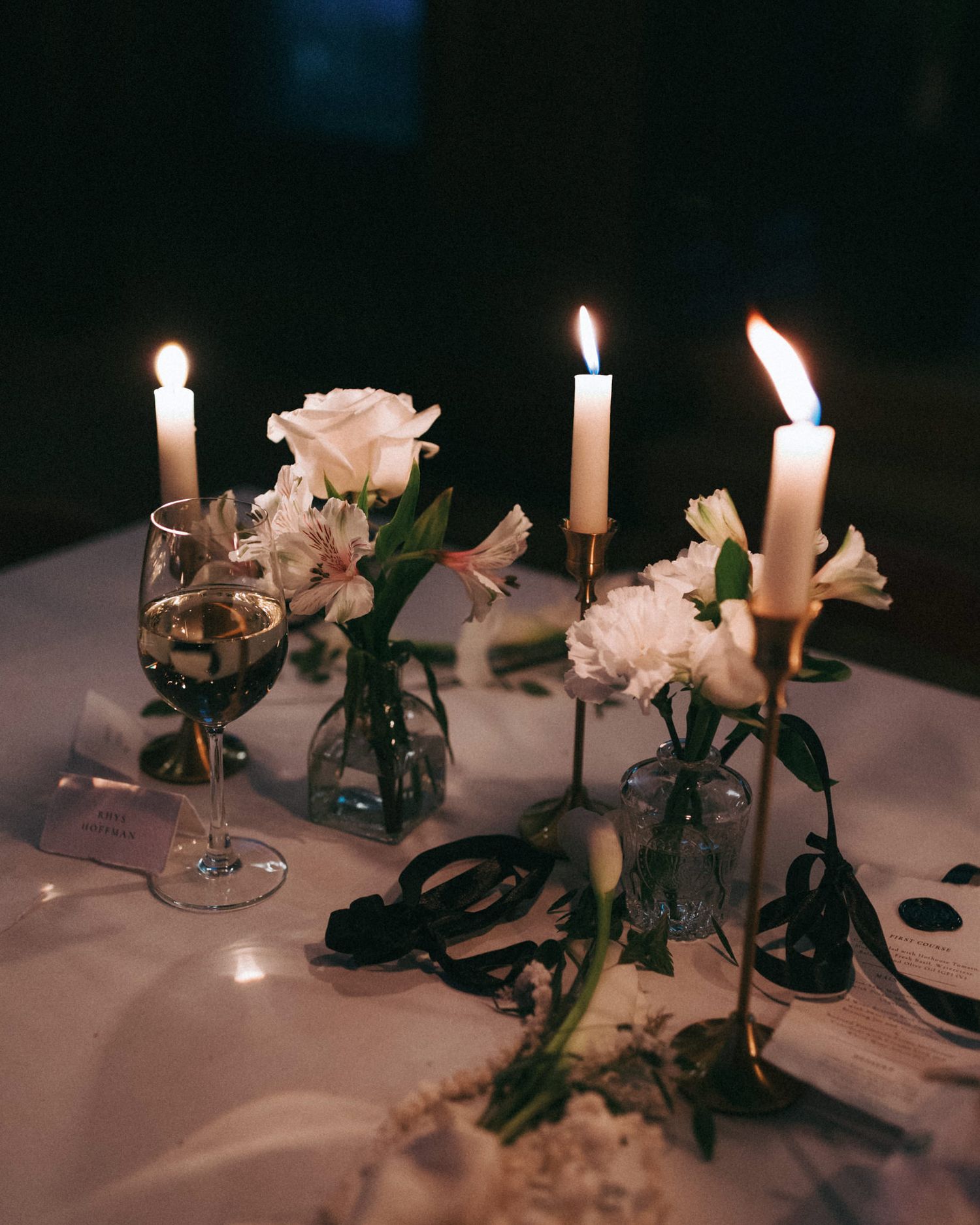 Romantic candlelit wedding table setting with pink roses and delicate floral arrangements.