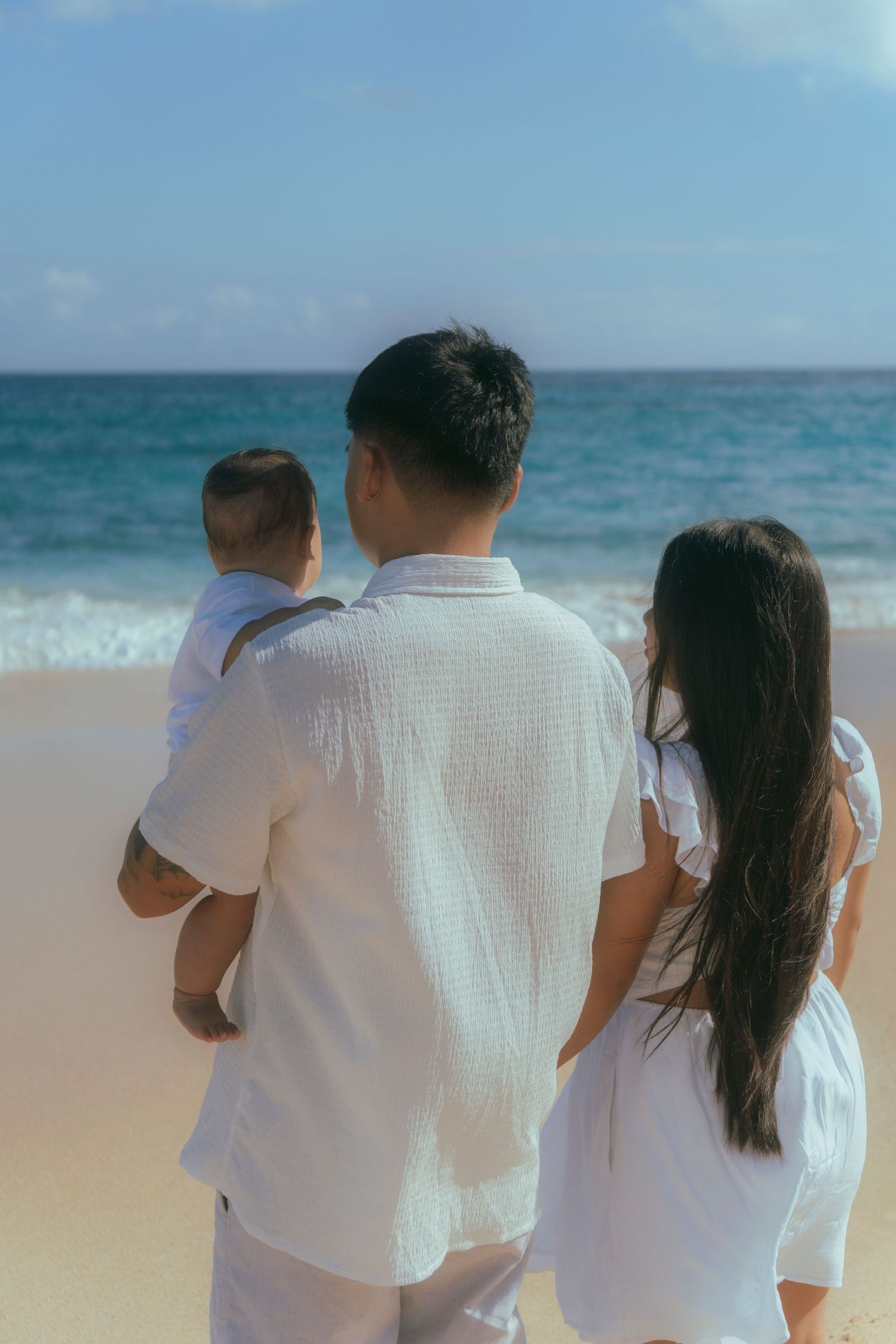 Family cuddled together on a beach at sunset in Oahu