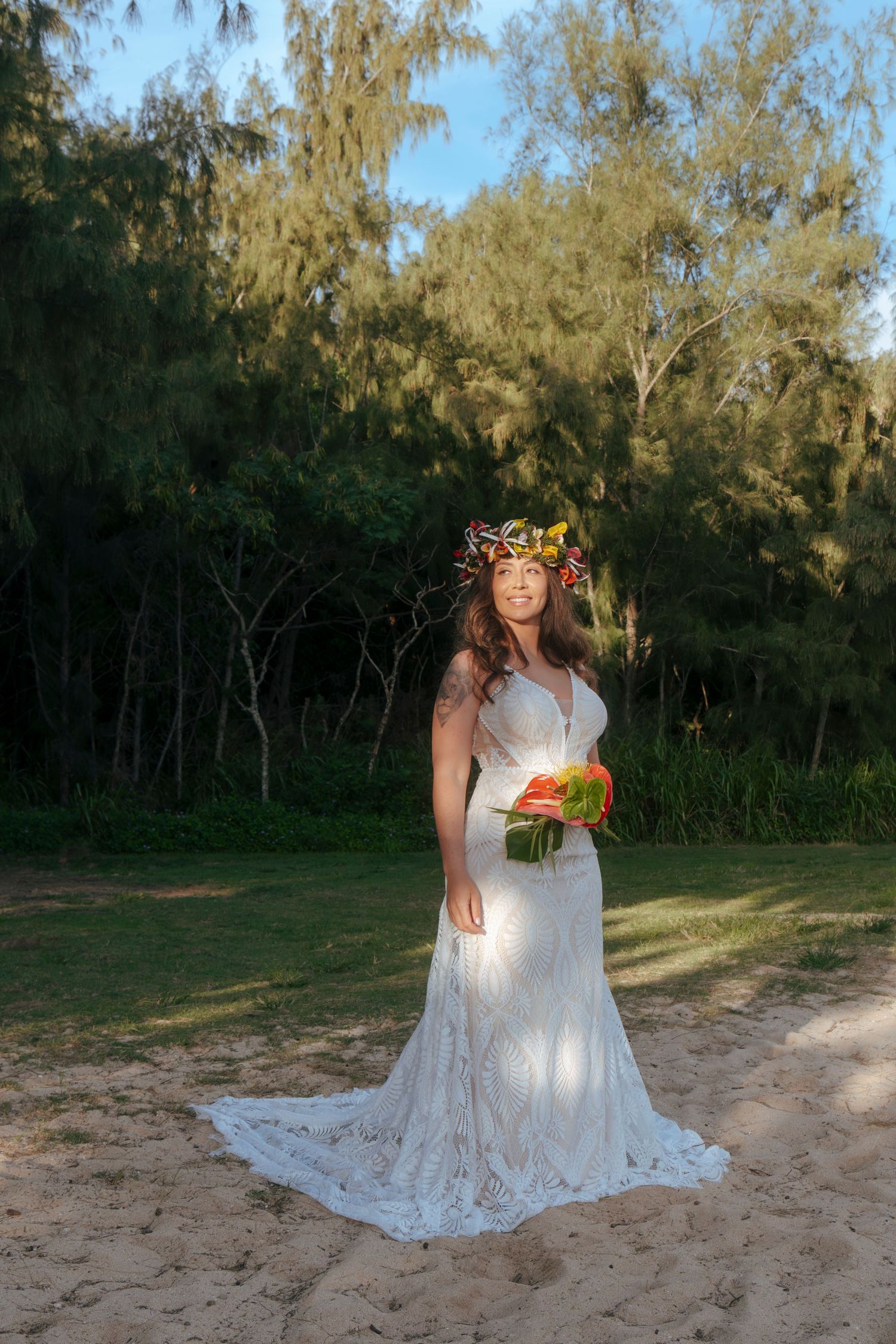Barefoot bride standing in shoreline with bouquet and sunset glow