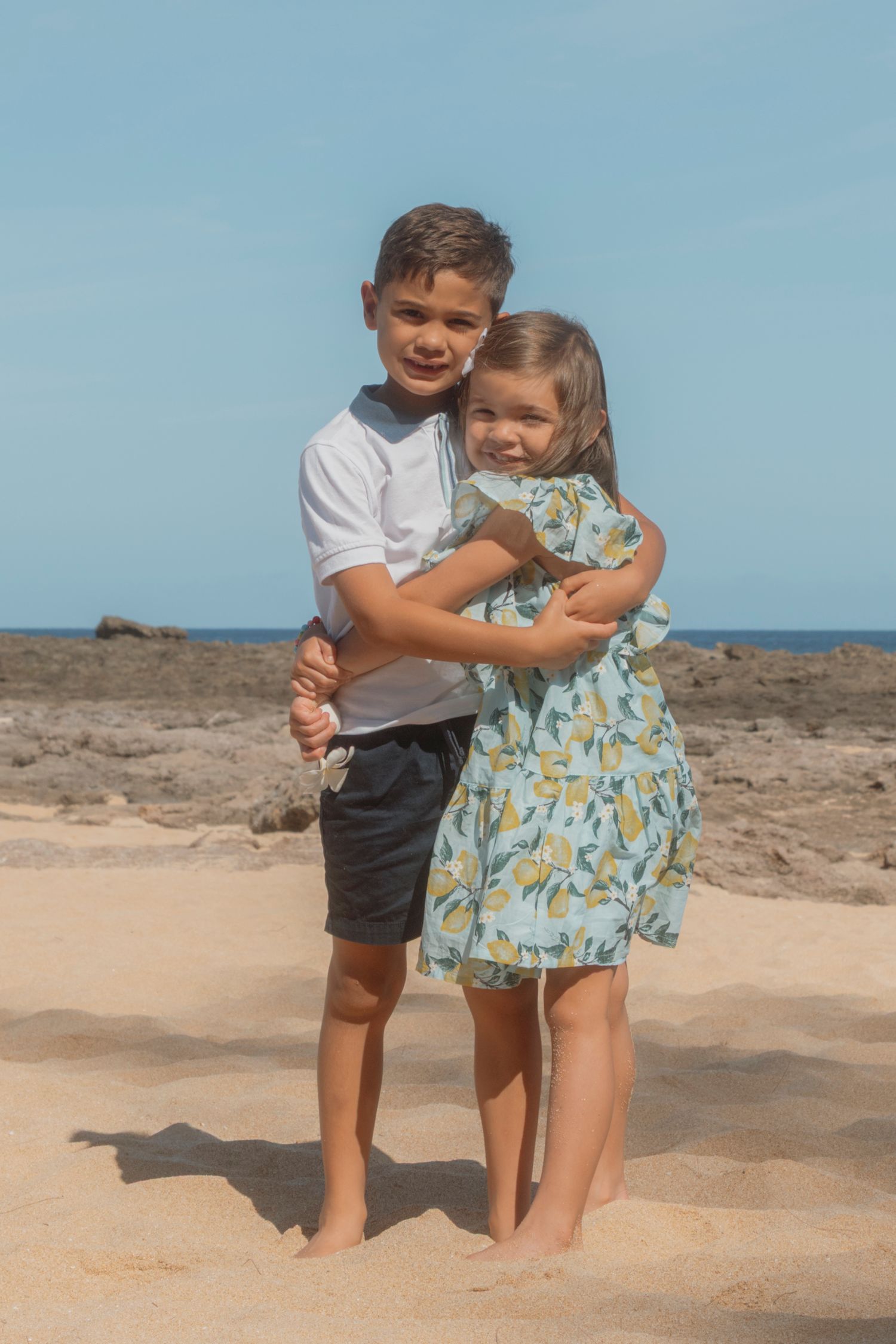 Siblings laughing together on the shoreline during Hawaii vacation photos