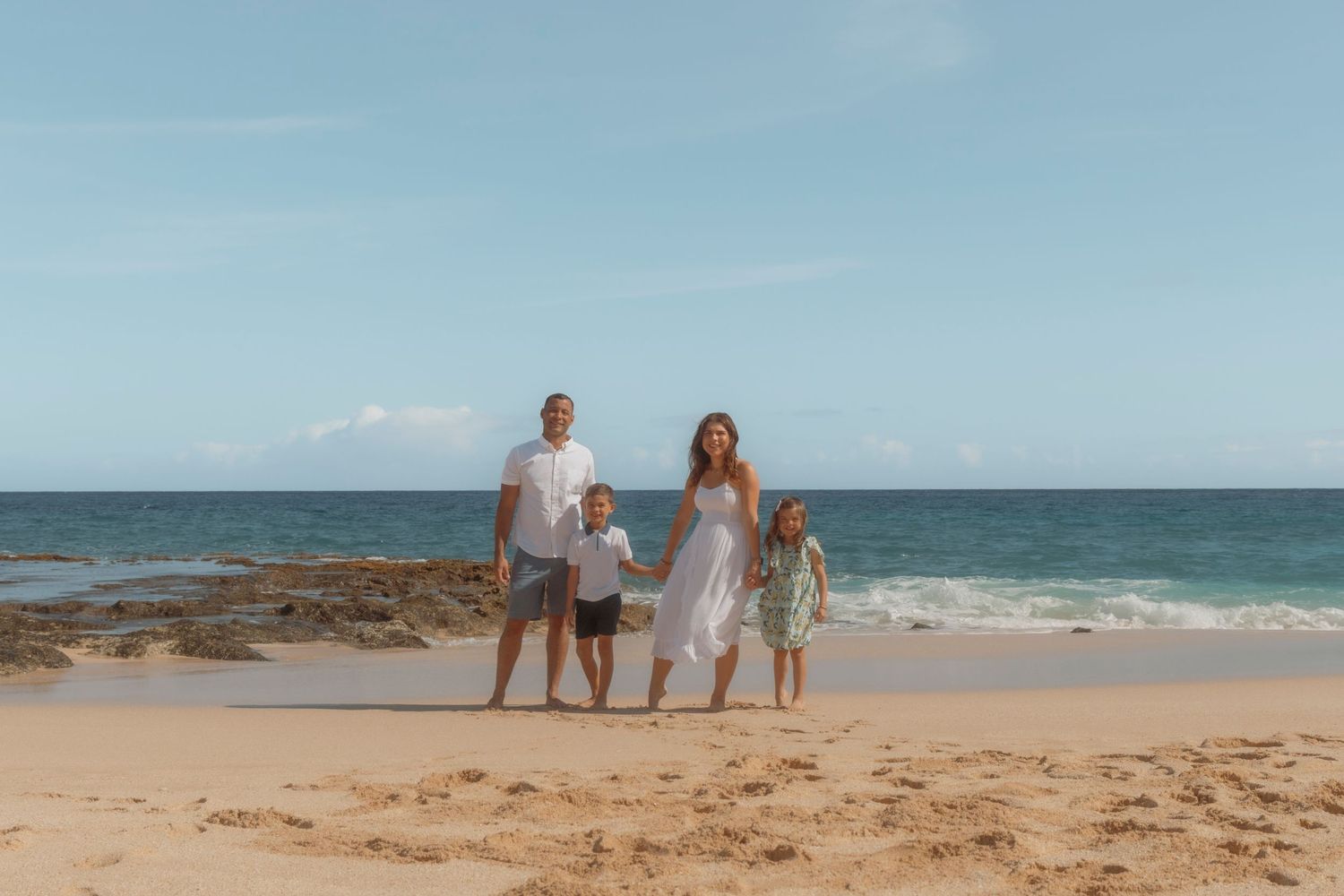 Family walking hand in hand along the beach in Oahu at sunset