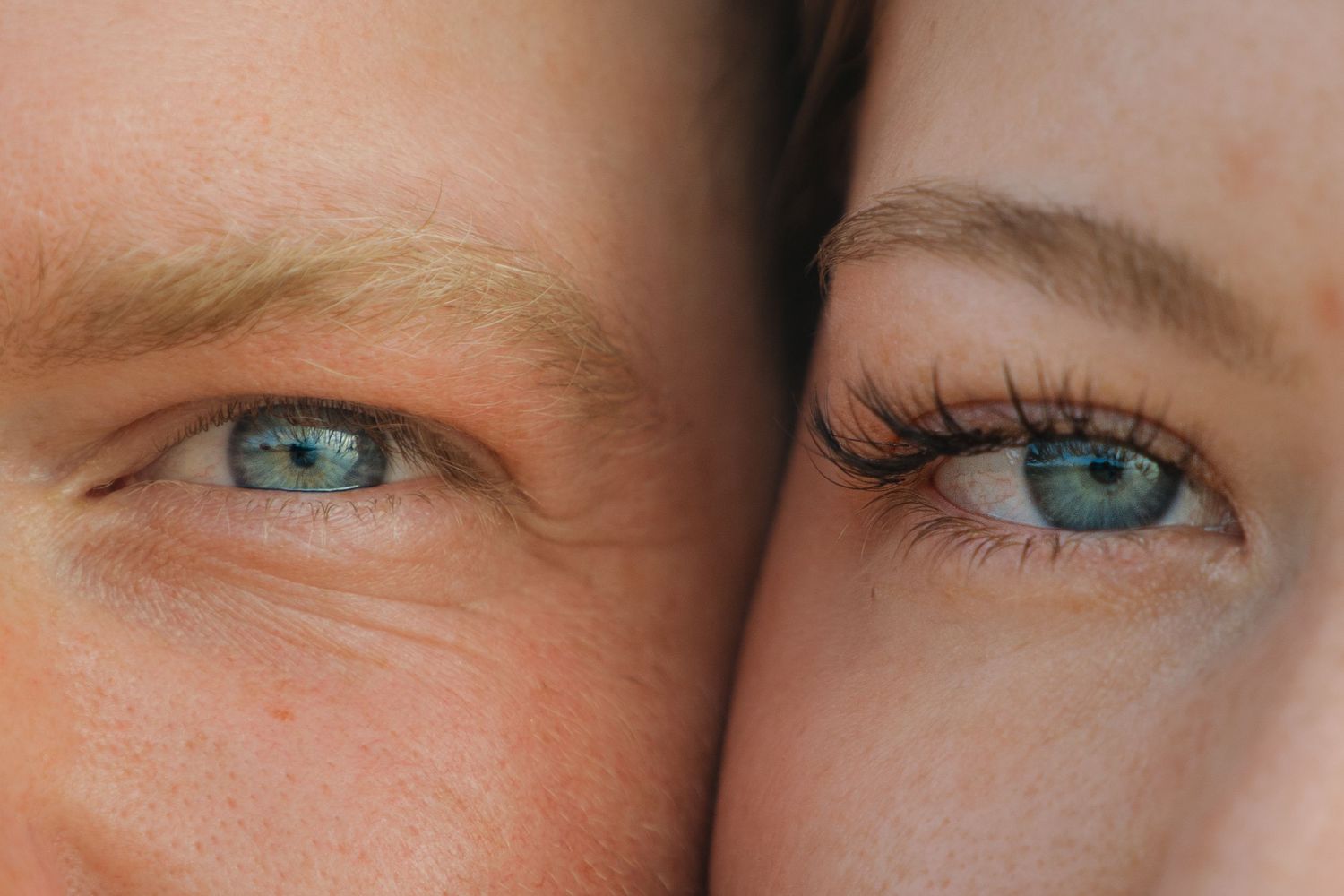 Close-up of two people with striking blue eyes pressed together side by side.