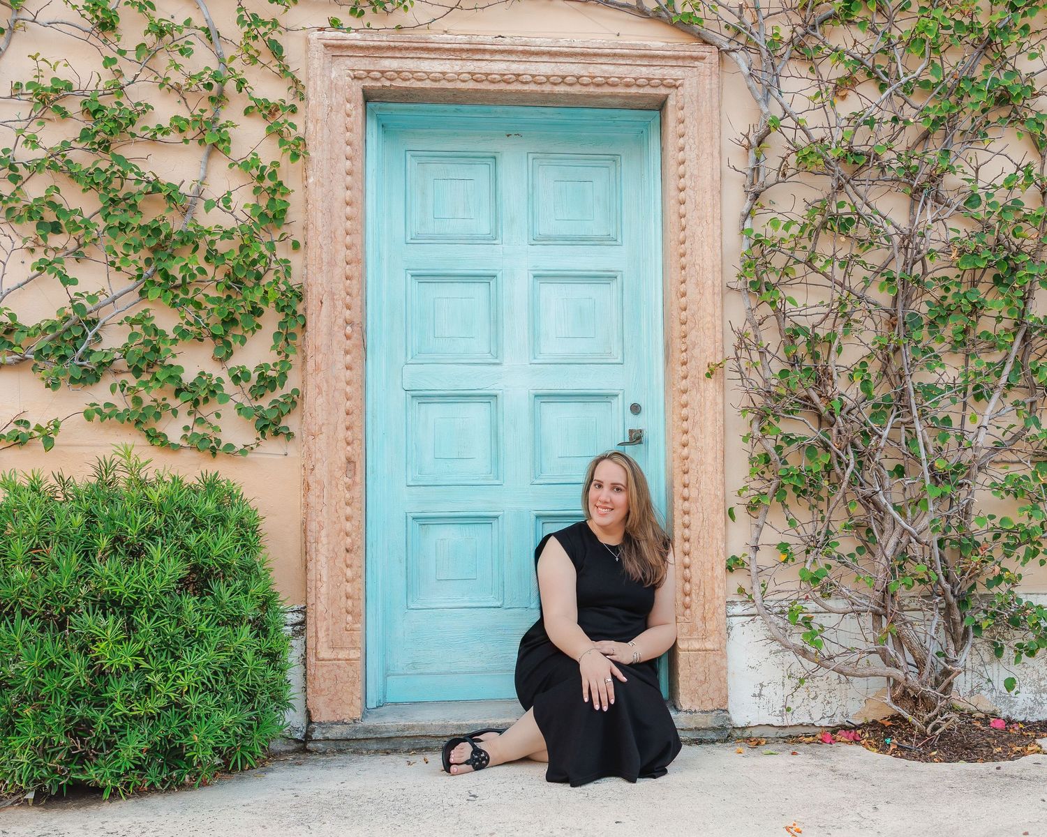 A turquoise blue door on a peach stucco wall with climbing green vines creates a Mediterranean-style entryway.