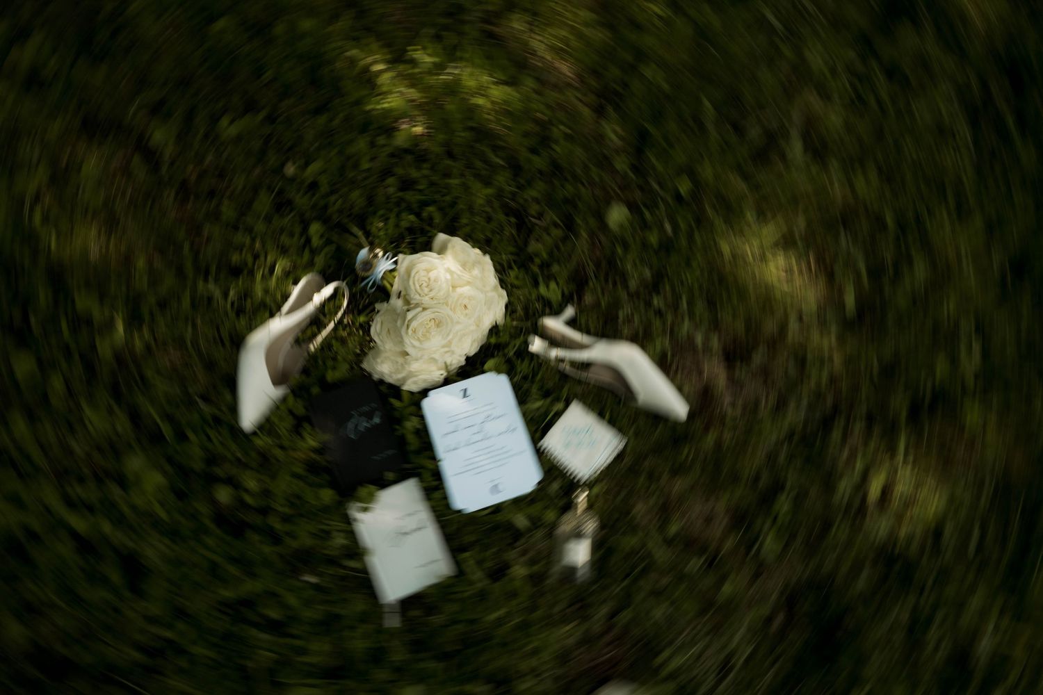 Aerial spinning shot of bride holding bouquet and vows surrounded by lush green grass.