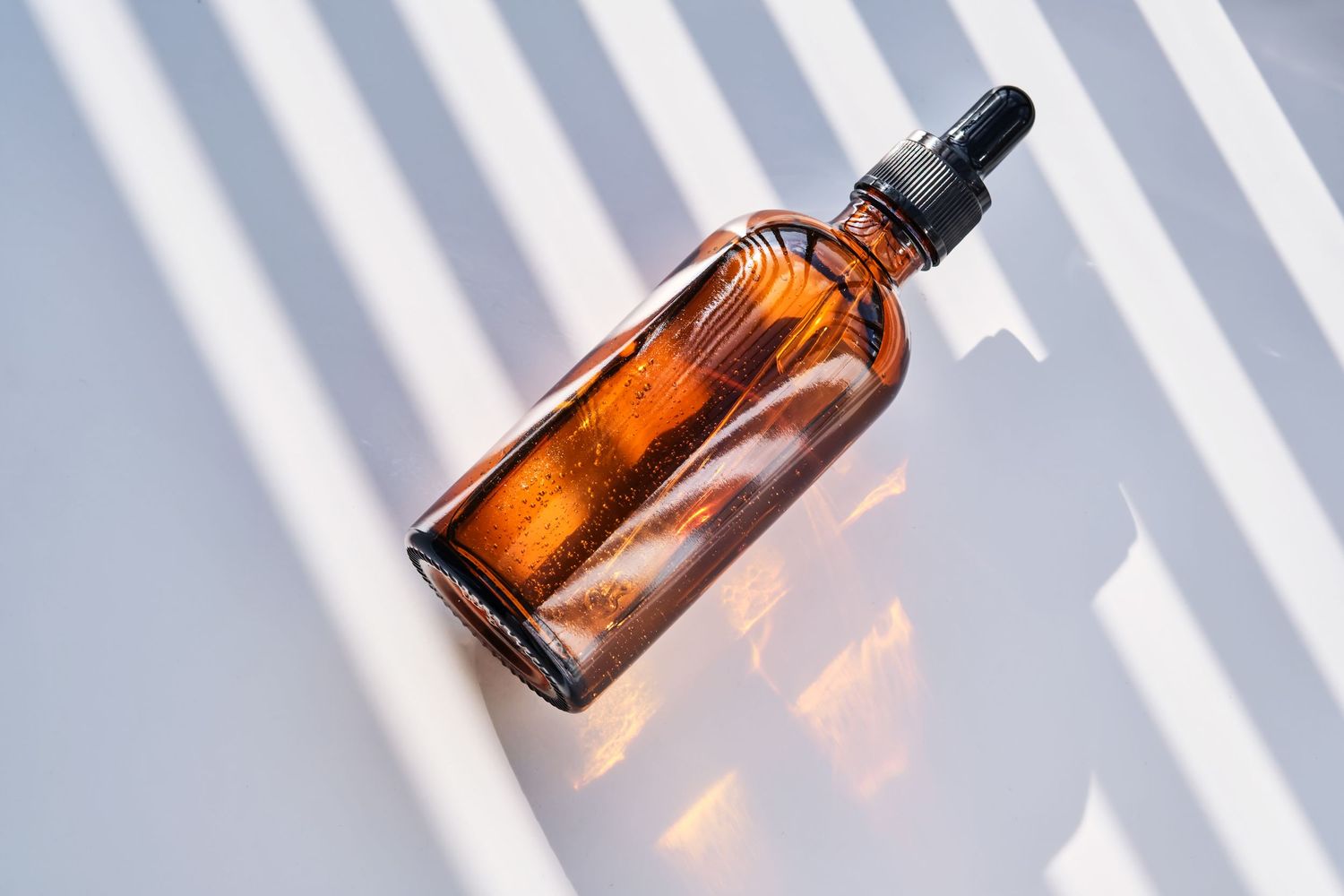 Glass bottle under sunlight with curtains shadow