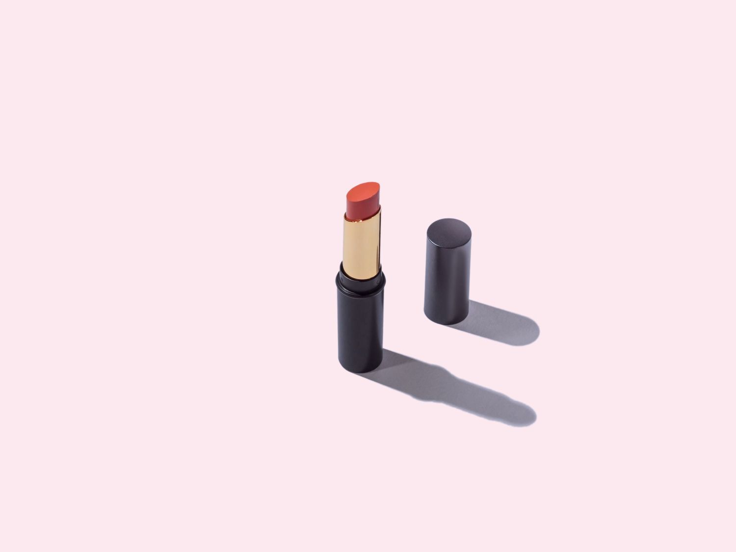 One red Lipstick and cap on a pink Background