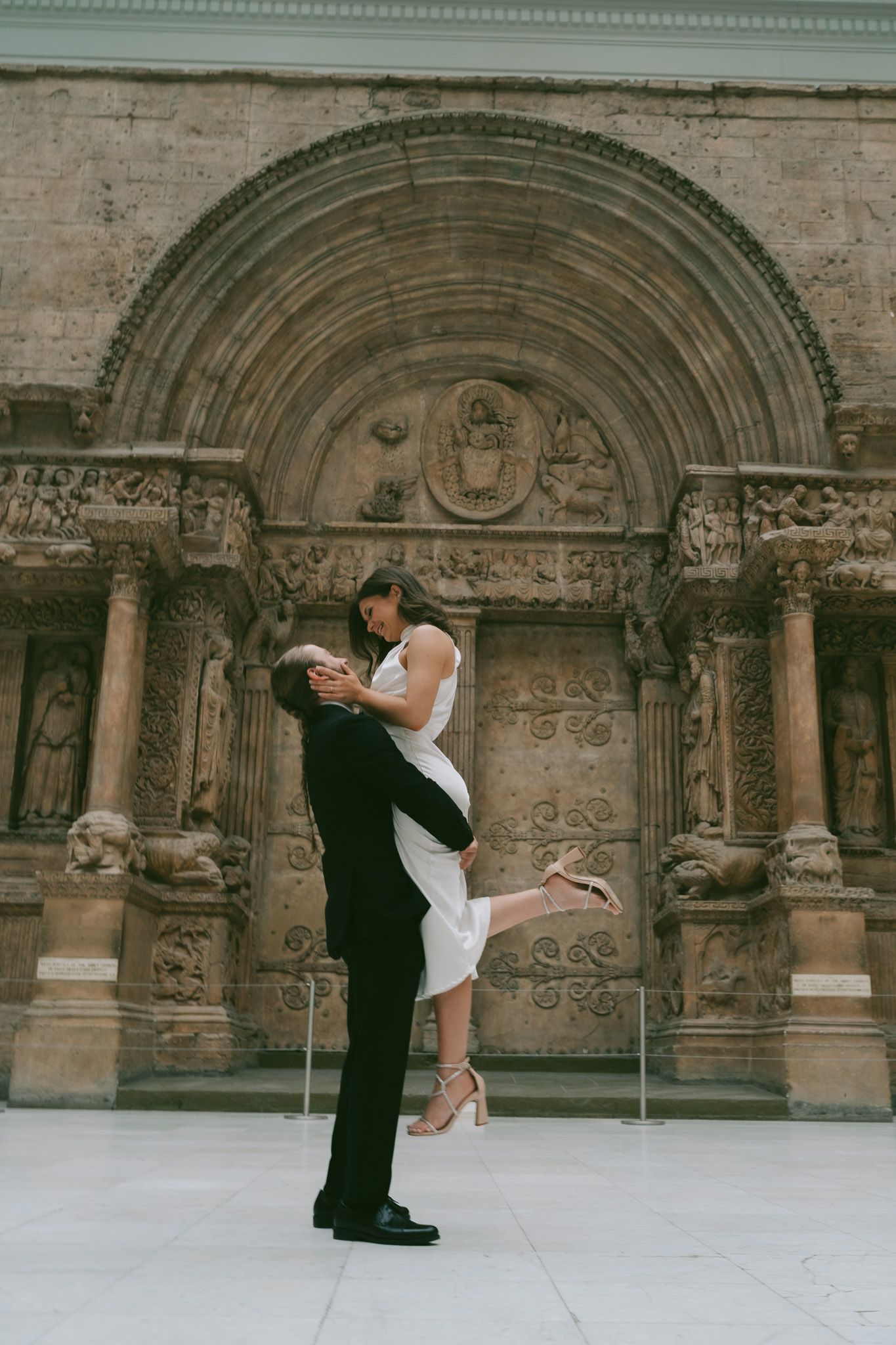 A romantic engagement photo sequence shows a couple dipping and embracing in front of an ornate stone church facade in carnegie museum.