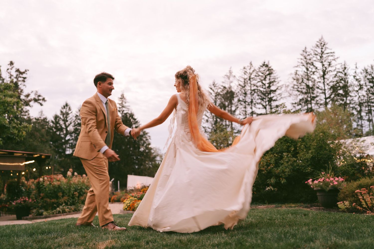 Couple dancing in an open field with flowing white wedding dress creating movement.