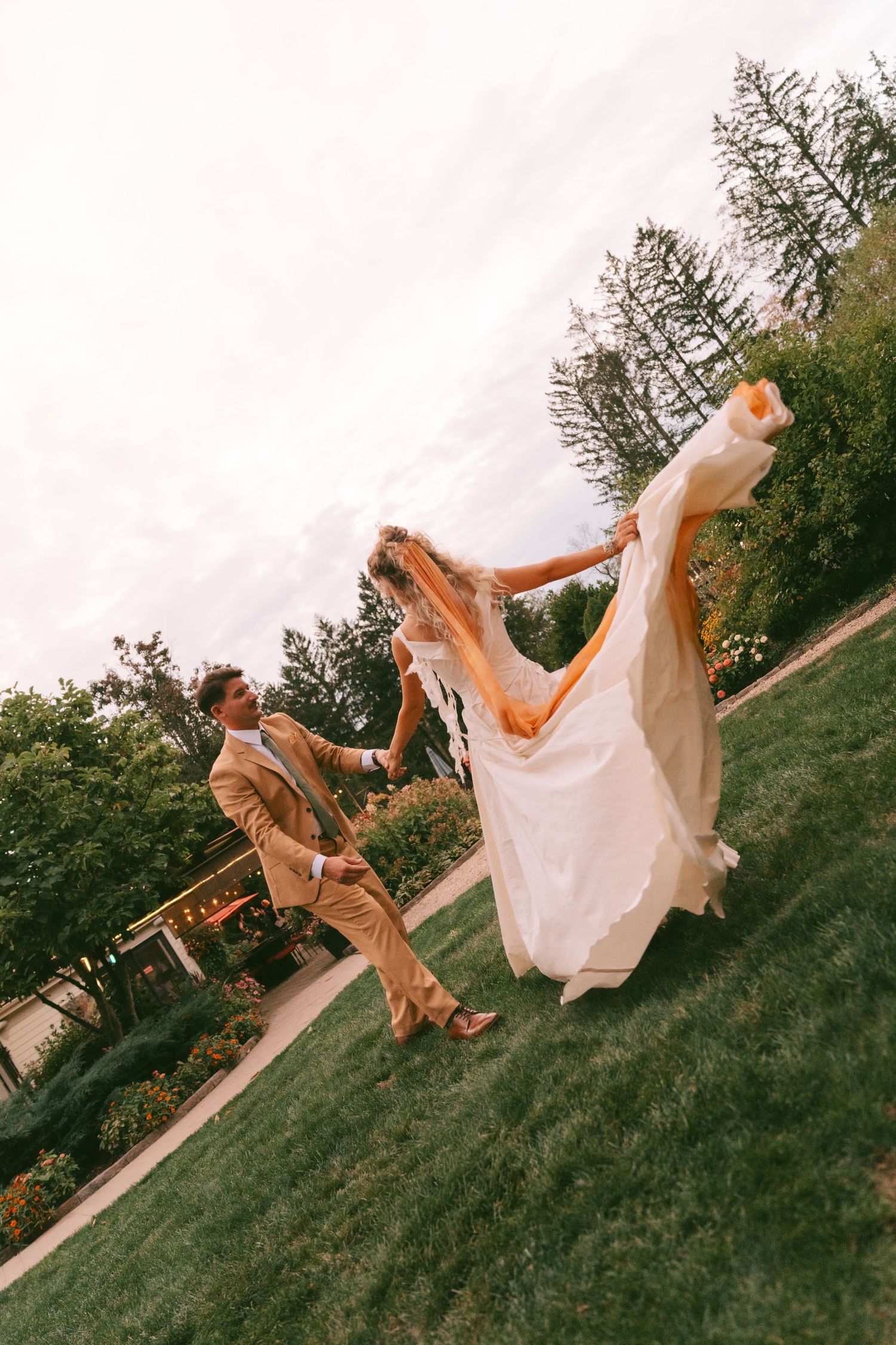 Playful sequence of a couple rolling down a grassy hill in formal attire.