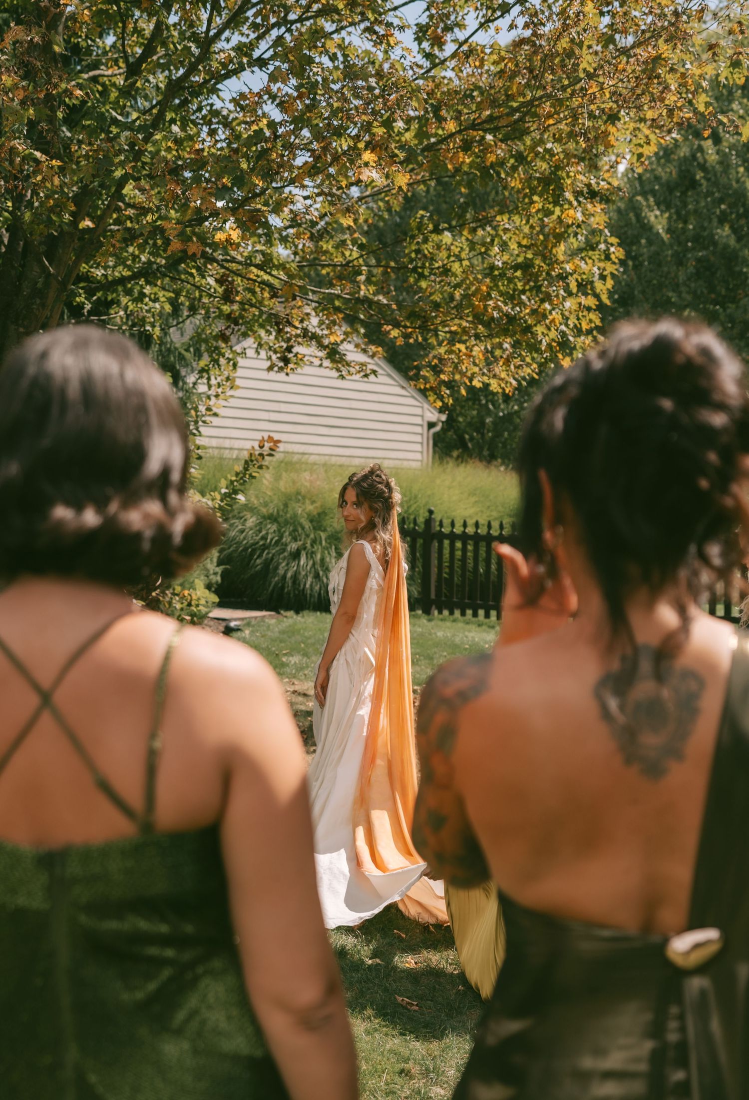 A group stands together outdoors under autumn trees with golden leaves during a sunny afternoon gathering.