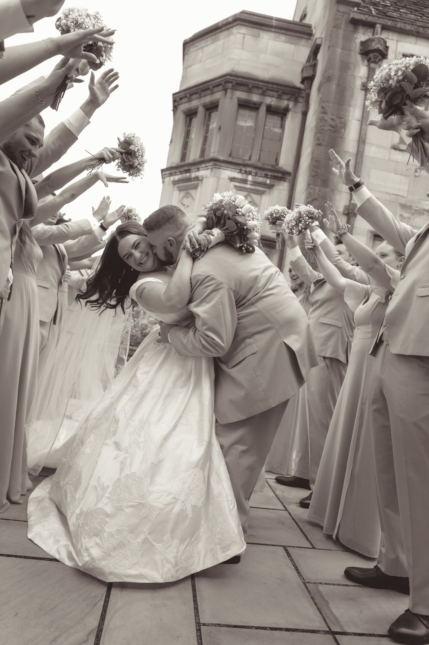A black and white photo series showing a wedding couple dancing and dipping in elegant poses on stone steps.