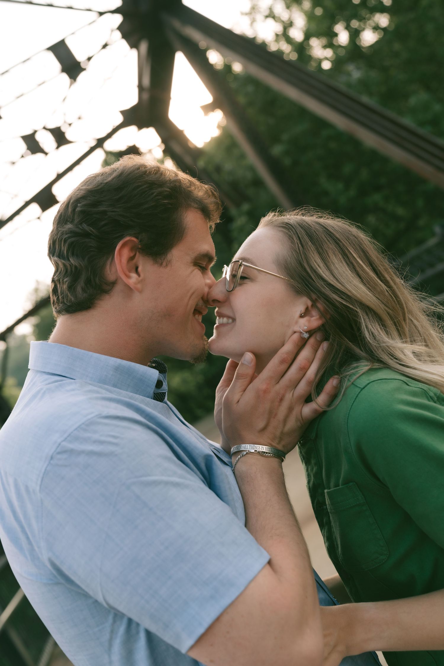 A tender romantic moment shared between two people on a bridge at sunset.