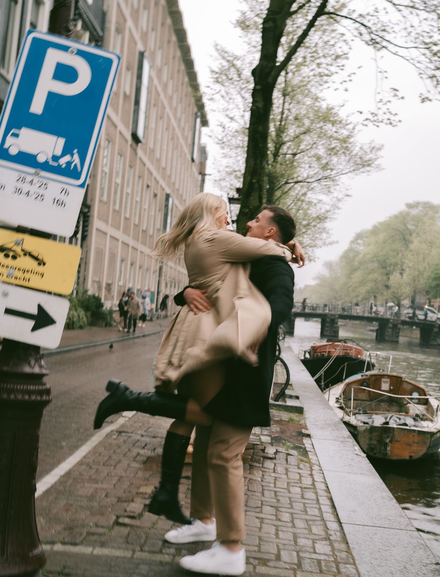 Playful dance sequence on a cobblestone street in Amsterdam with parking signs visible.