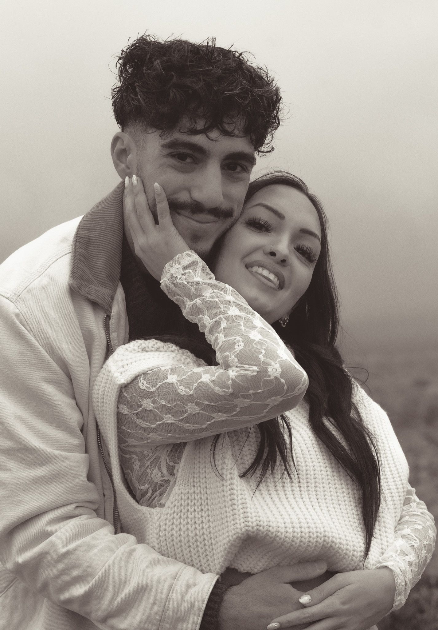 Intimate black and white portrait of a couple in white knit sweaters.