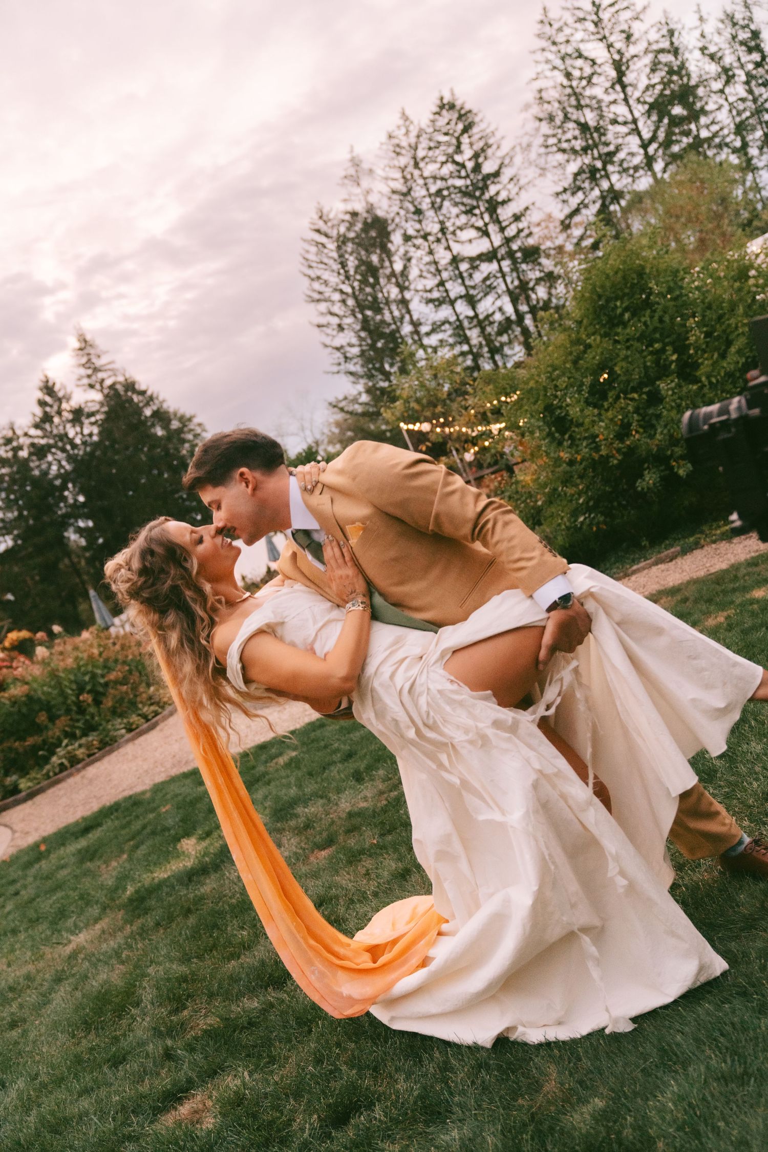 Artistic outdoor photo featuring flowing white dress and orange fabric in motion.