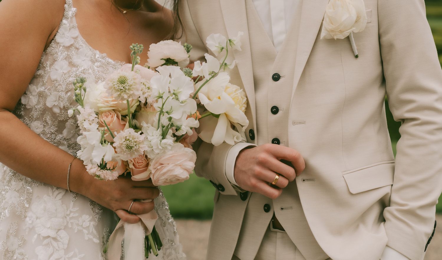 Wedding party dressed in elegant white and beige attire posing together outdoors.
