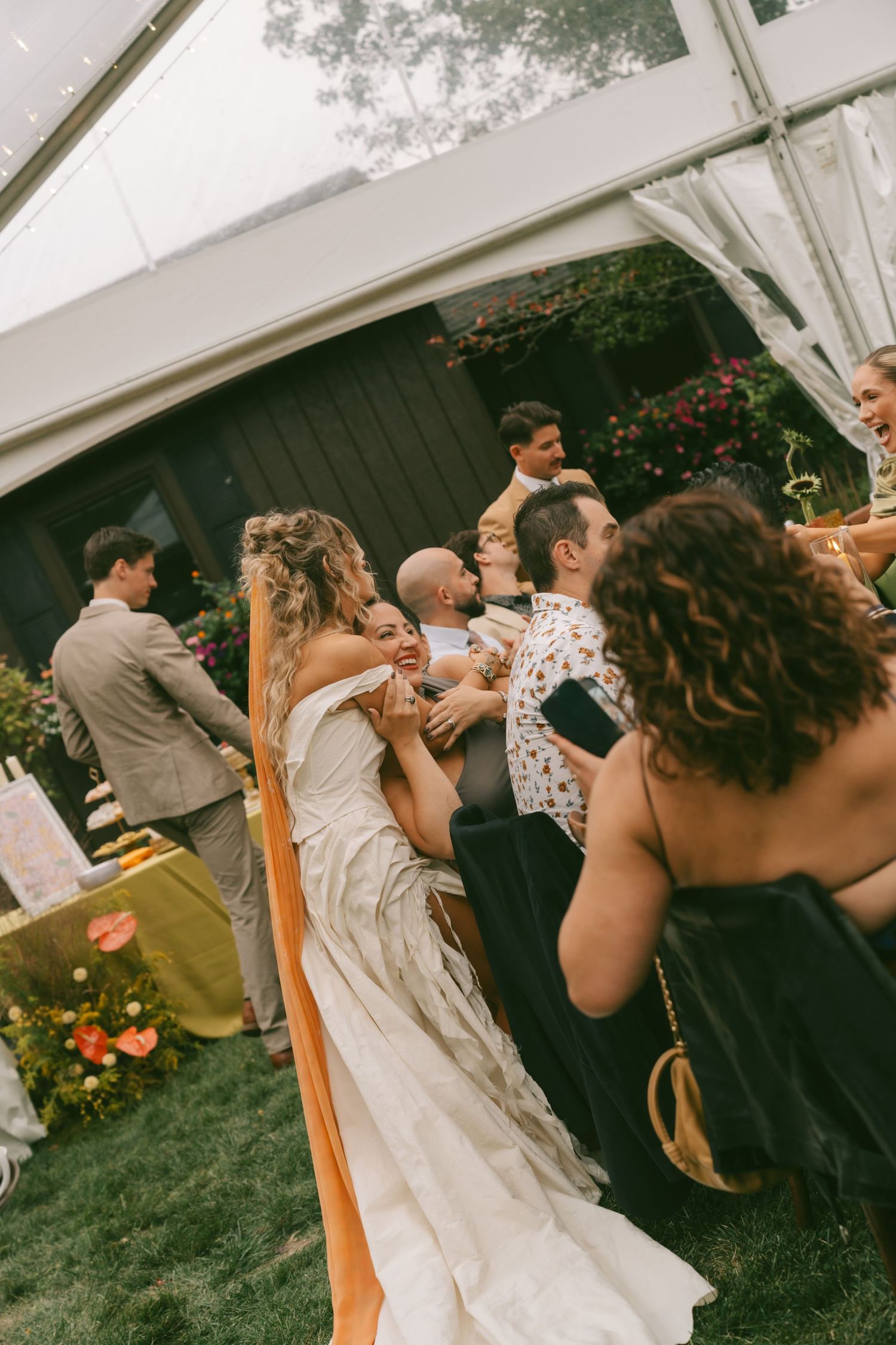 Wedding celebration with guests dancing under a white tent during an outdoor reception.
