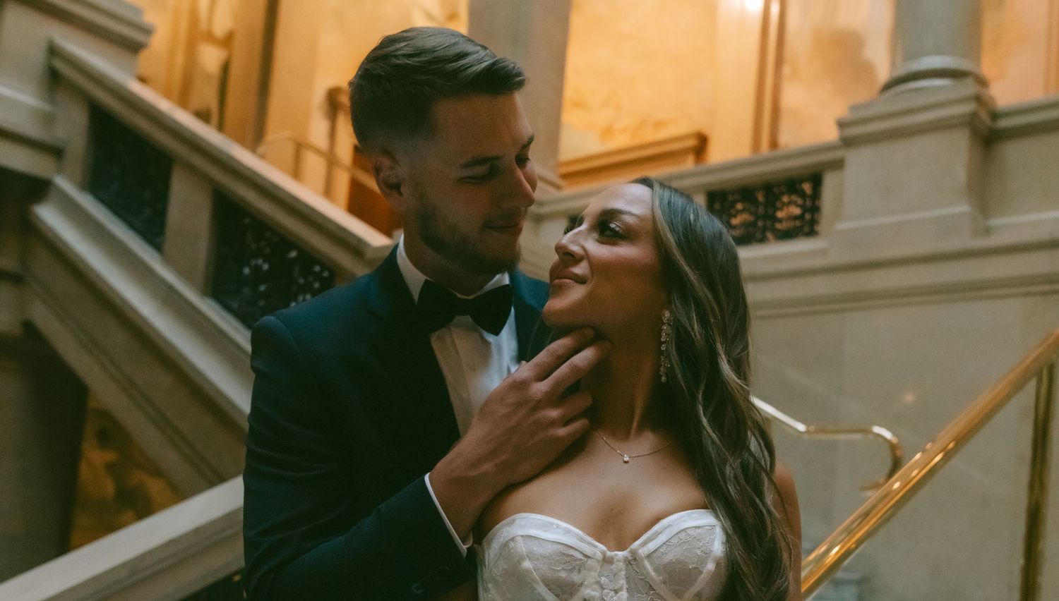 Intimate wedding moment captured in a luxurious indoor setting with golden lighting.