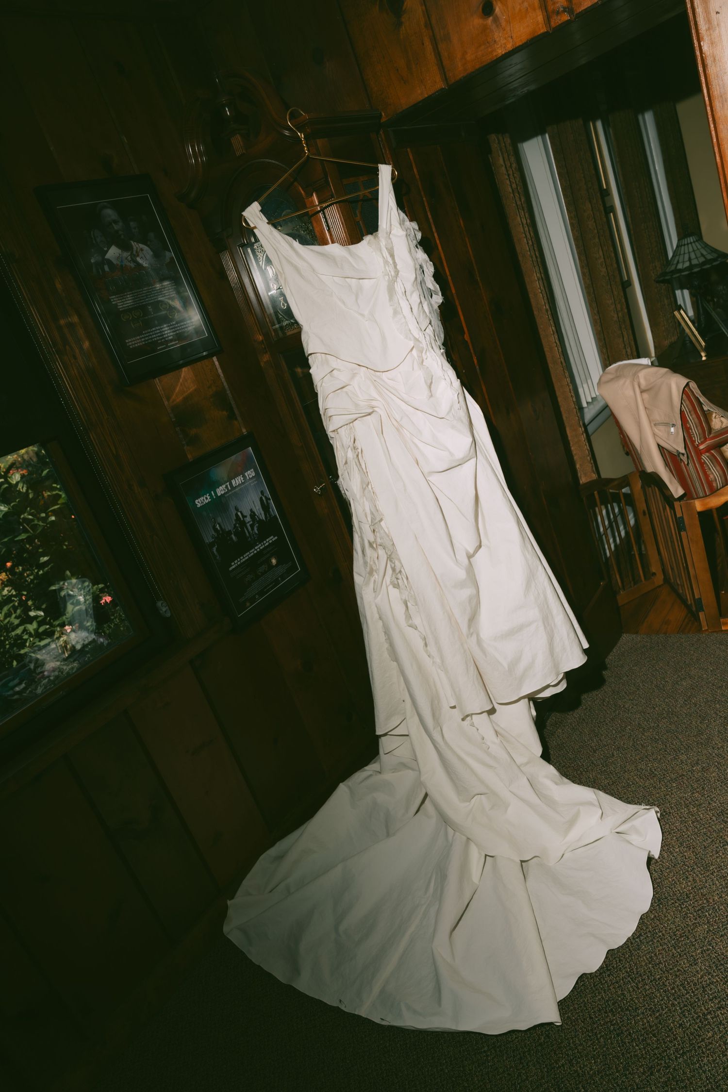 White wedding dress displayed in a rustic wooden interior setting.
